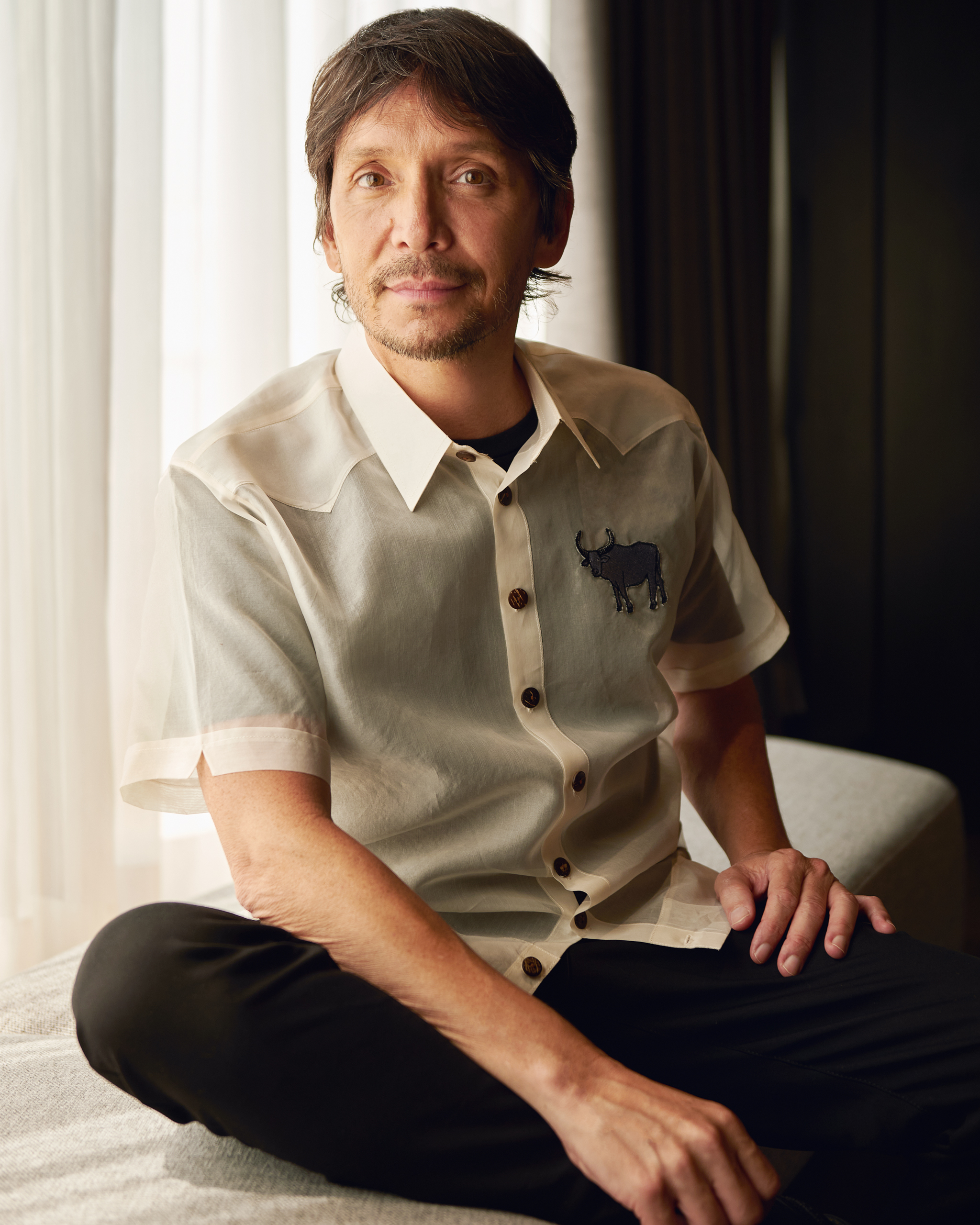 Ken Paves wearing a white polo against a bright curtain background