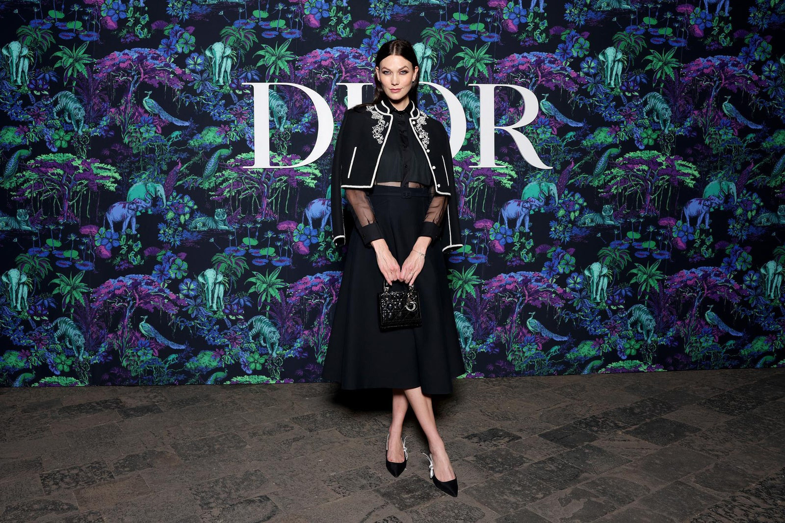 Dior Fall/Winter 2023 Show In Mumbai Karlie Kloss wore a Dior Cruise 2023 black embroidered wool jacket, black silk shirt and a black wool skirt.