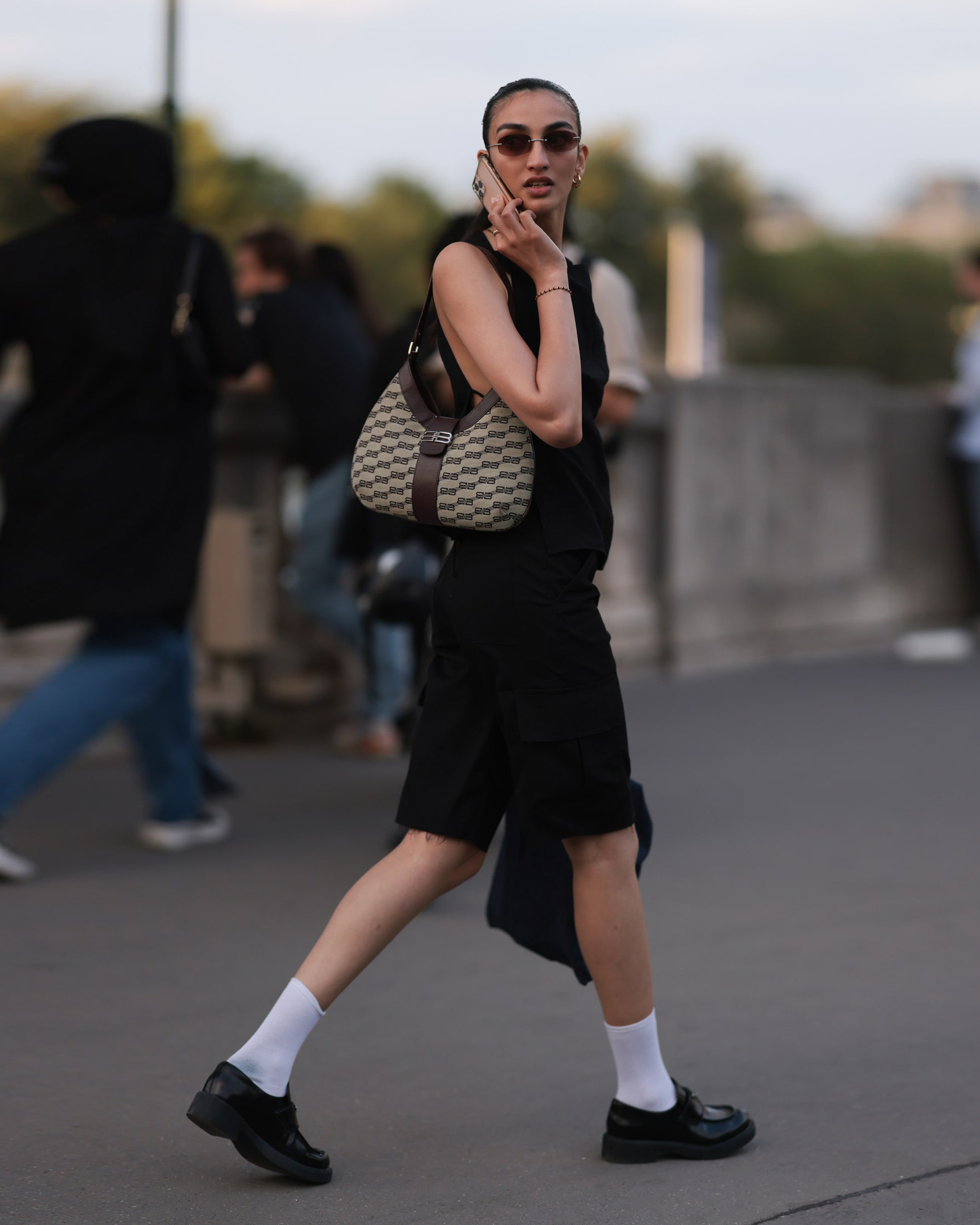 woman walking on the phone wearing black loafers and white socks