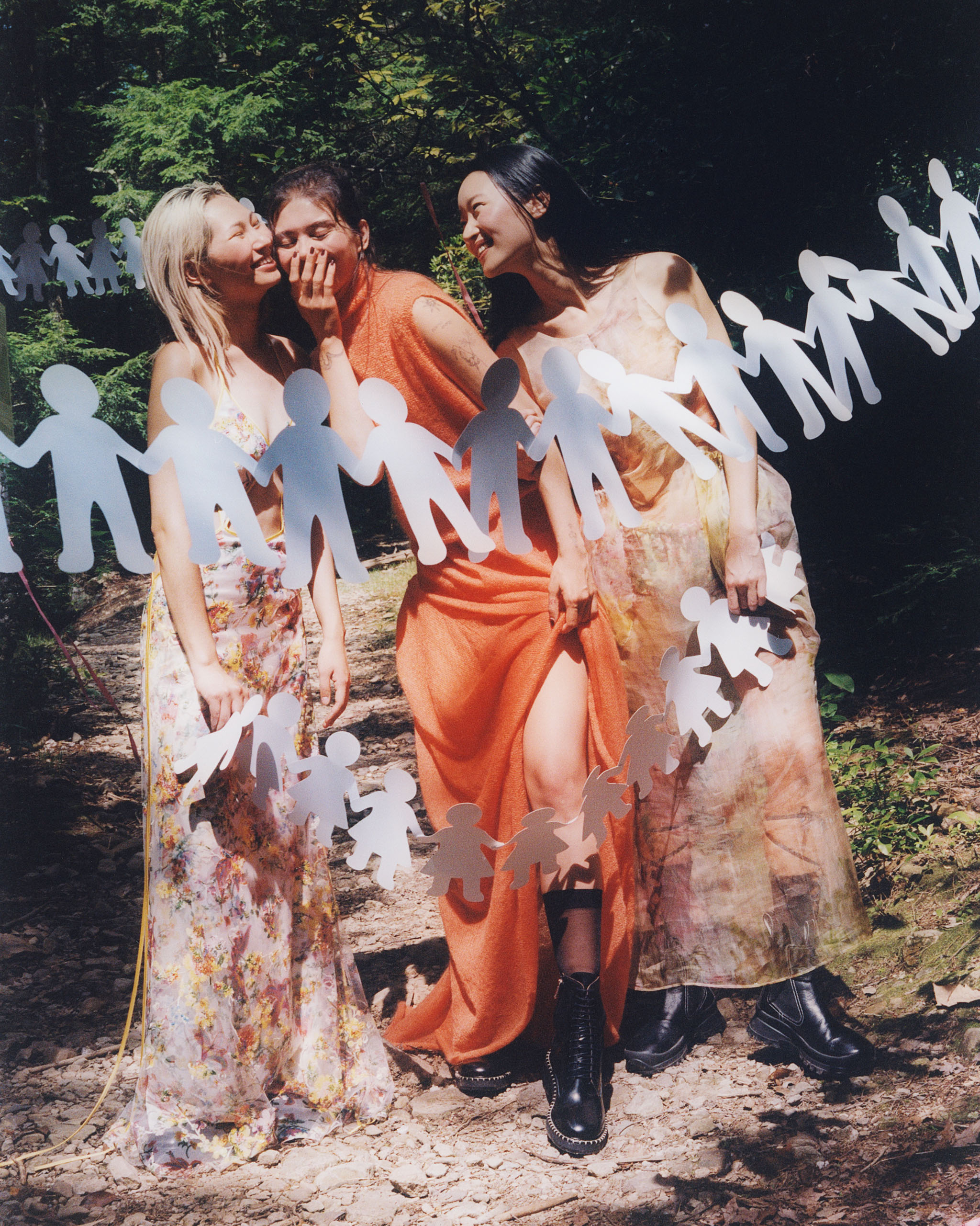 Diana Carl, Jiwon Ra and Megan Rodrigues laughing and smiling with paper cut out of people