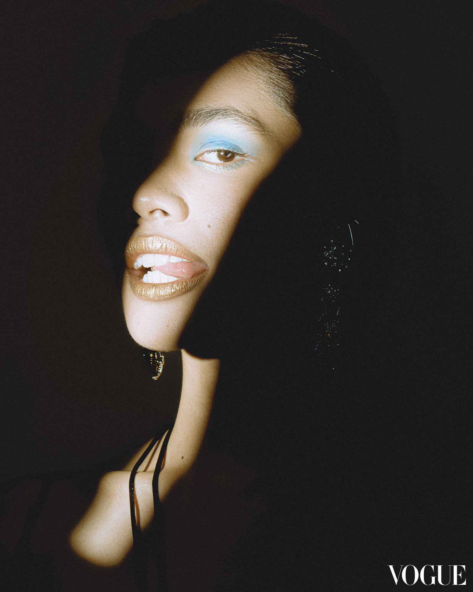 a woman with blue eyeshadow biting her tongue