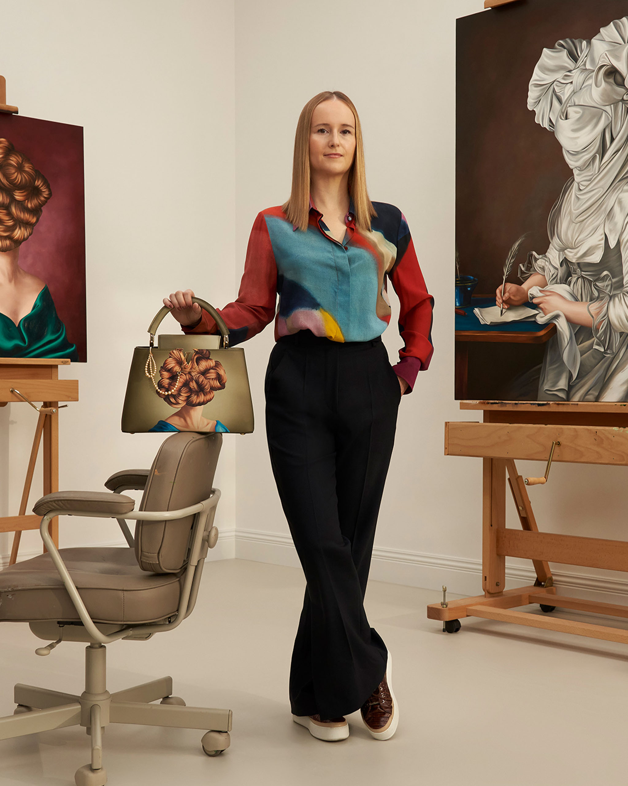 Artist Ewa Juskiewicz posing with her Artycapucines and portrait paintings.