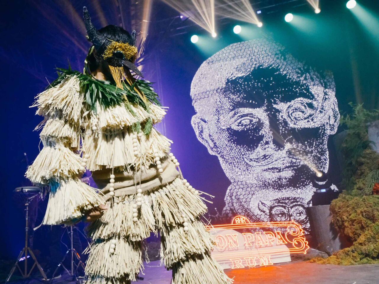 A mythical creature of Sugarlandia dancing behind the digital image of Papa Isio.