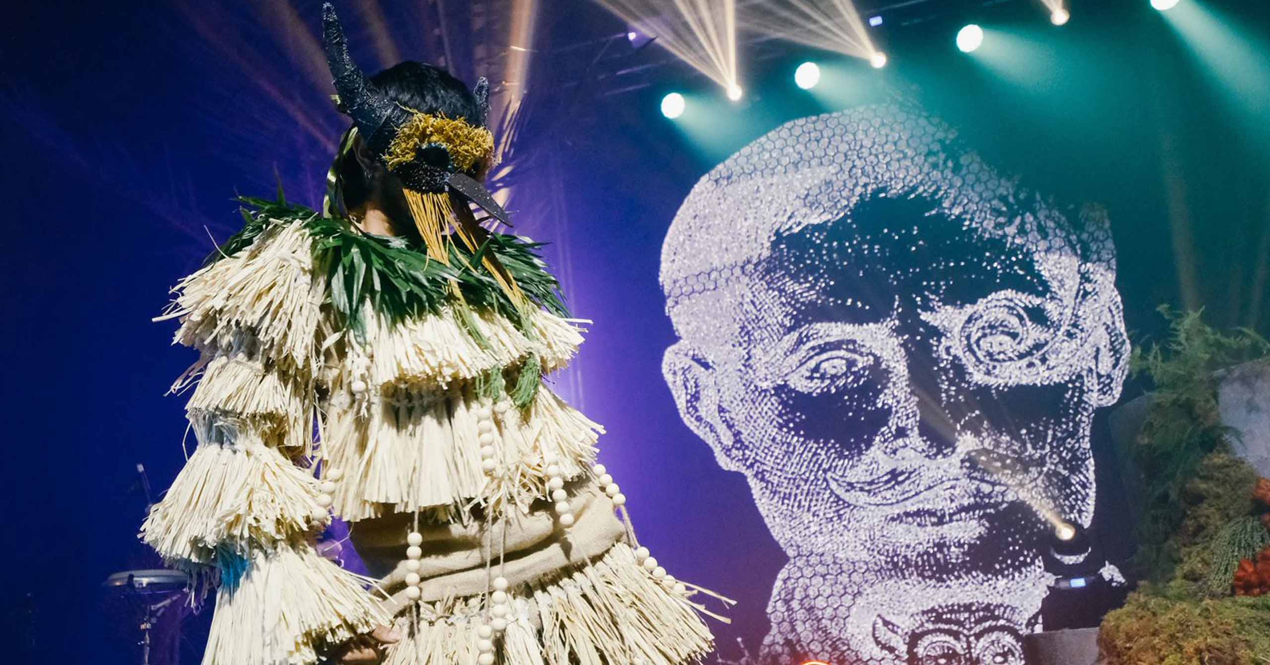 A mythical creature of Sugarlandia dancing behind the digital image of Papa Isio.