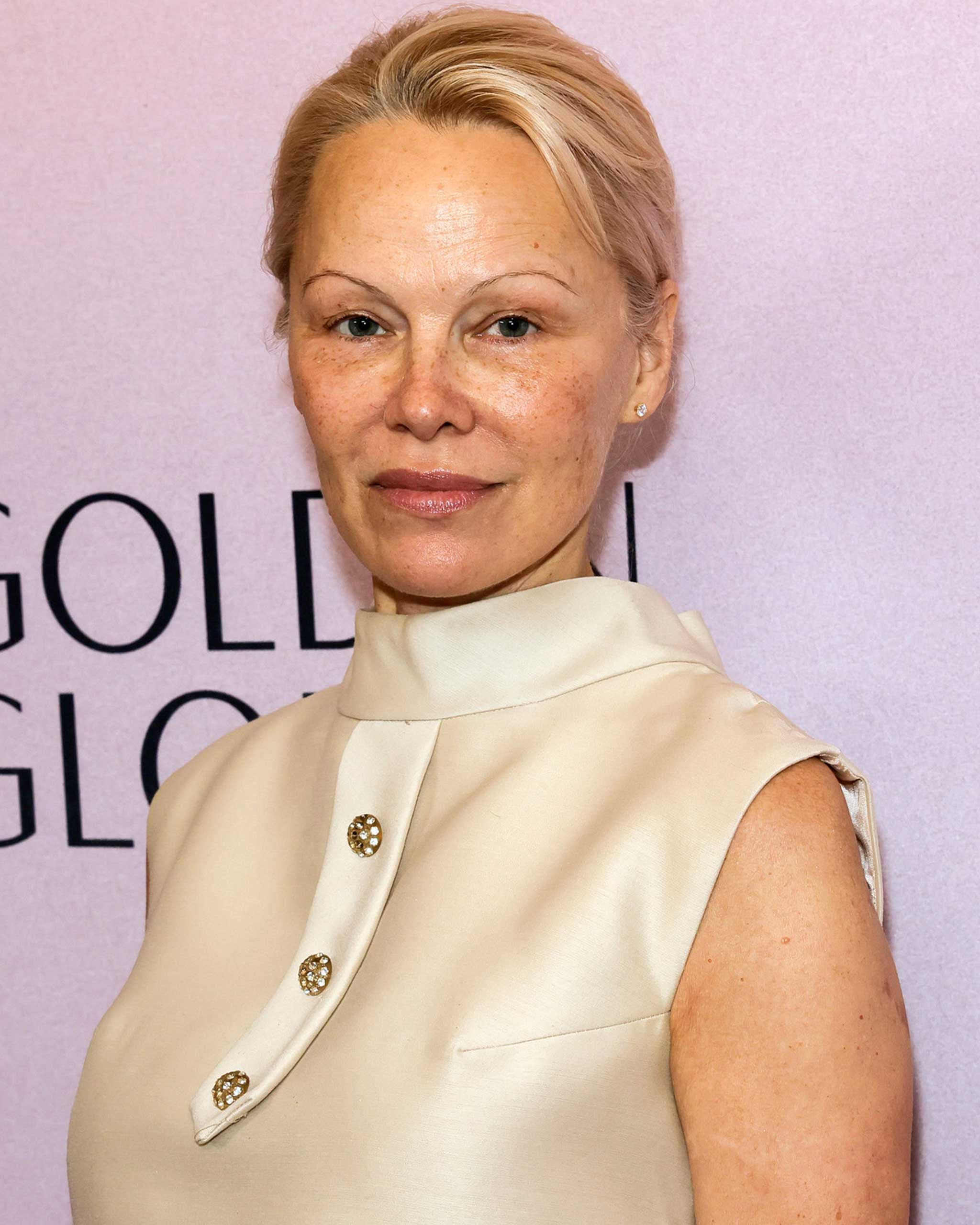 The Last Showgirl Actress Pamela Anderson wears a cream, silk a-line dress from the 60s, its buttoned up, rounded collar.