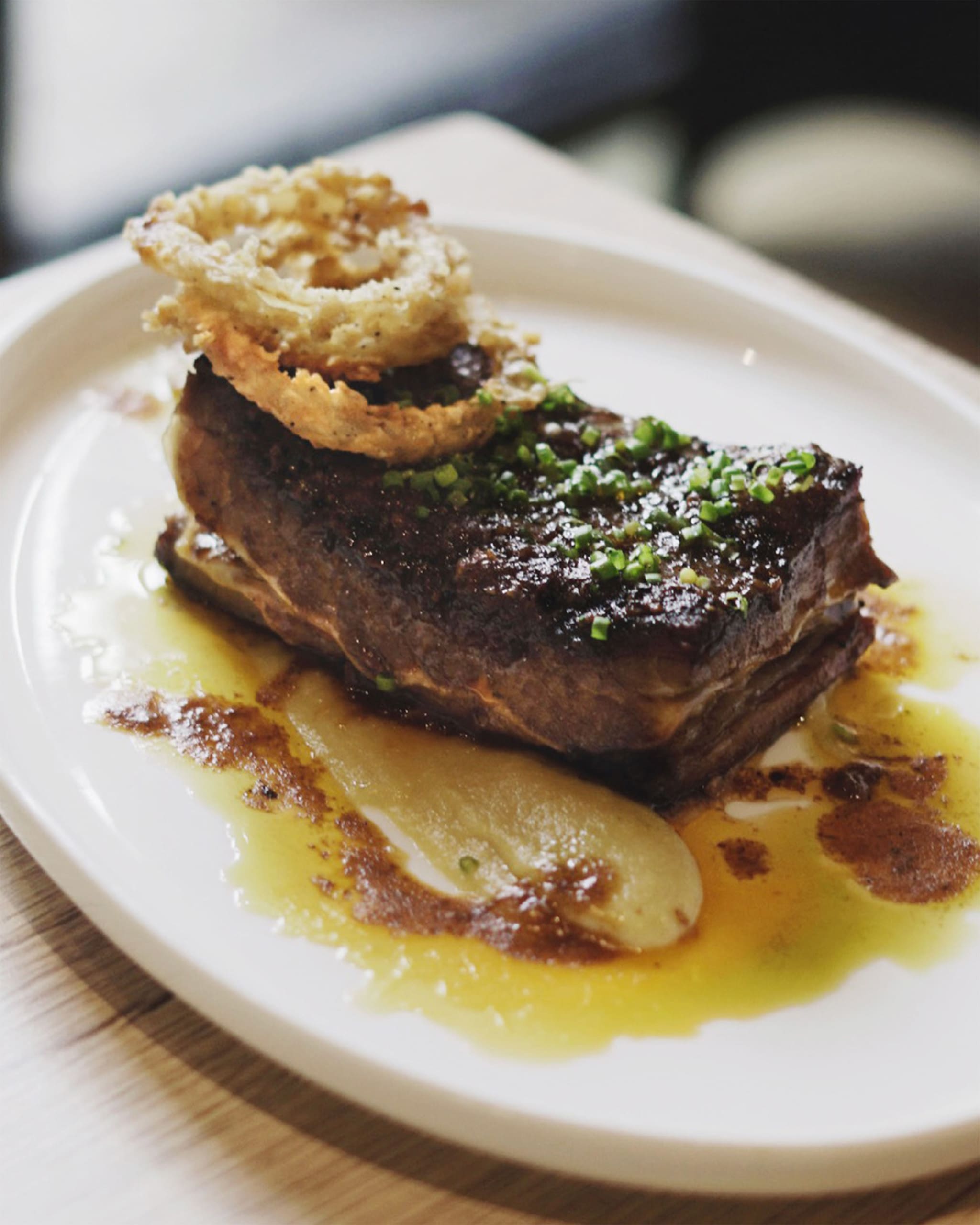 Roasted Beef Belly Bistek plated with Bistek Jus, Fried Onions and Onion Soubise. Photographed by Andre Cesar