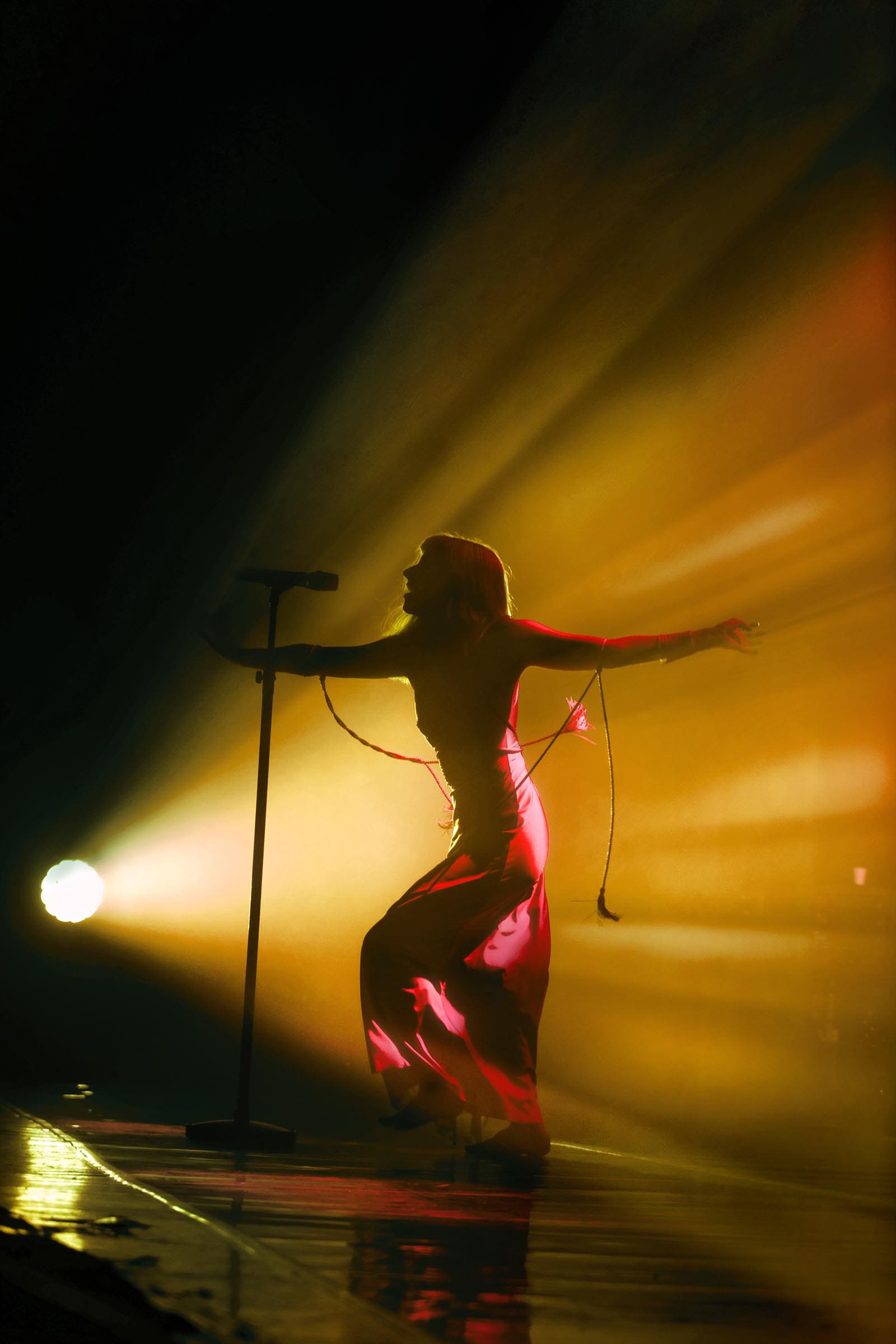 Photo of musician Aurora on stage bathed in yellow light.