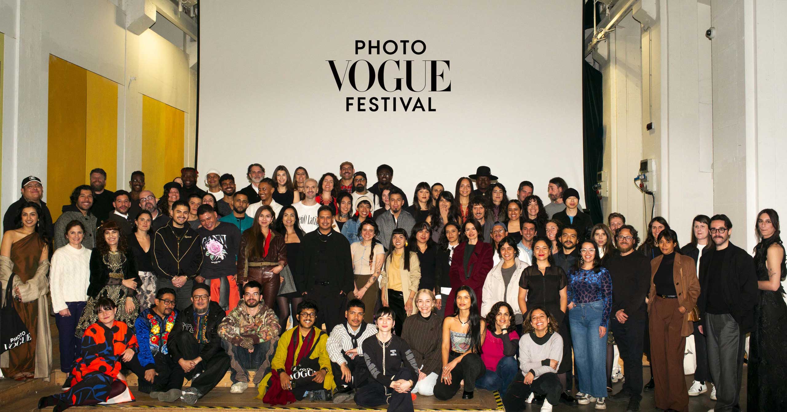 A big group of people photographed together in front of a wall that reads 