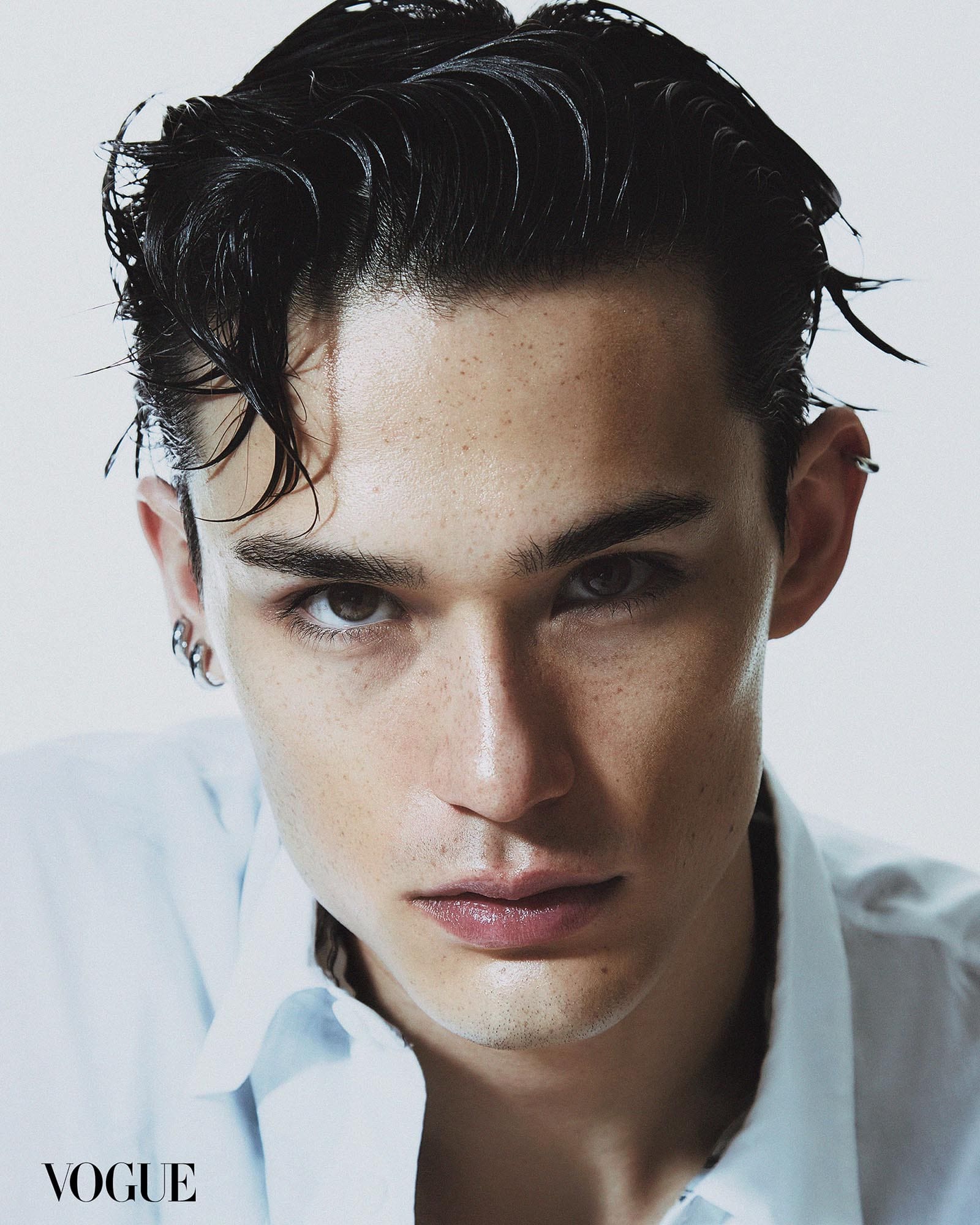 Alex Schlab in a close up portrait with gelled hair and silver earrings.
