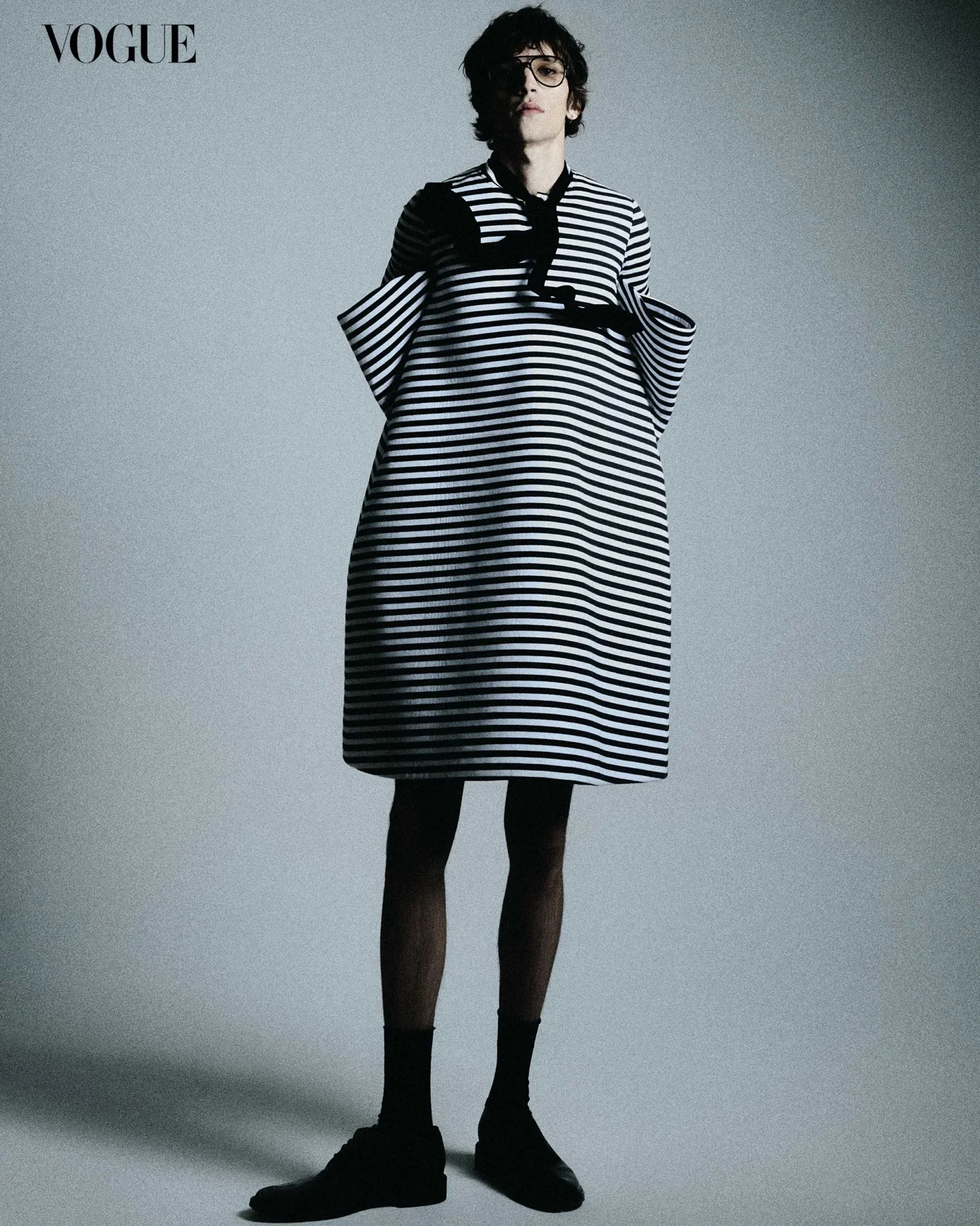 Eliseu wears Tom Ford glasses, Giorgio Armani tie, Loewe dress, and Maison MArgiela socks and shoes