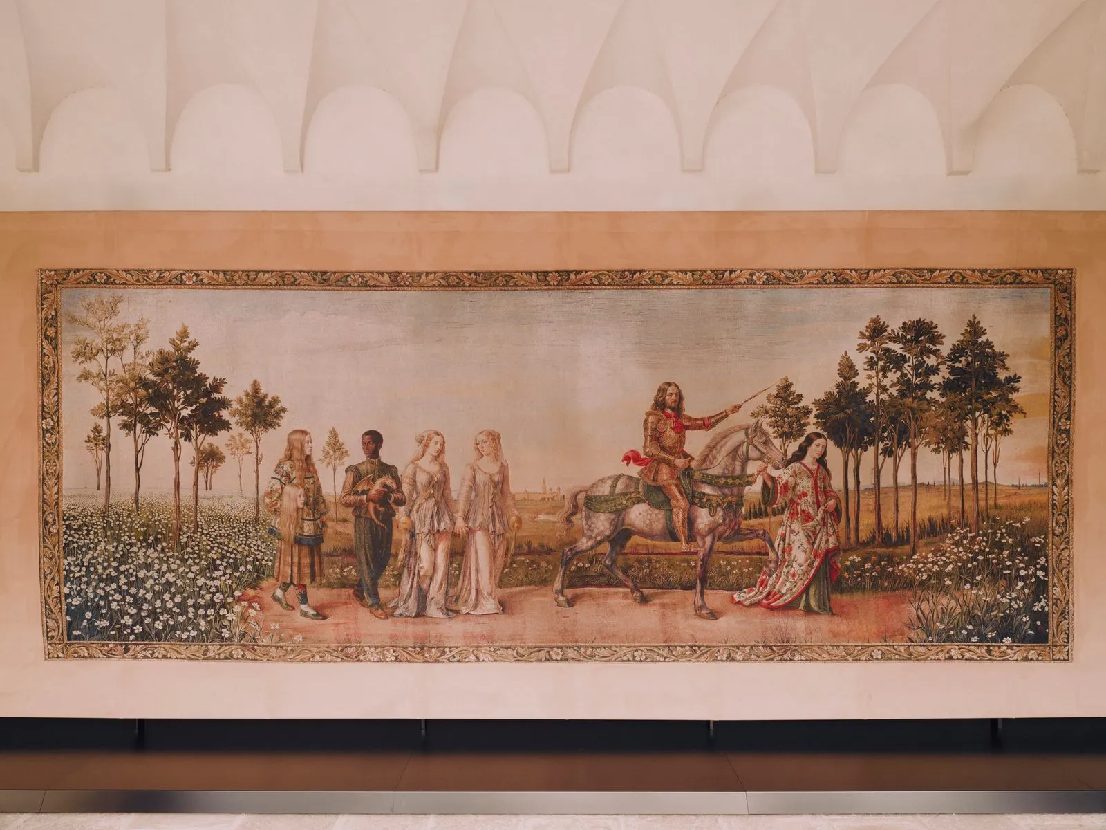 Medieval tapestry showing a knight on a white horse leading a procession of men and women through a flower-filled landscape.