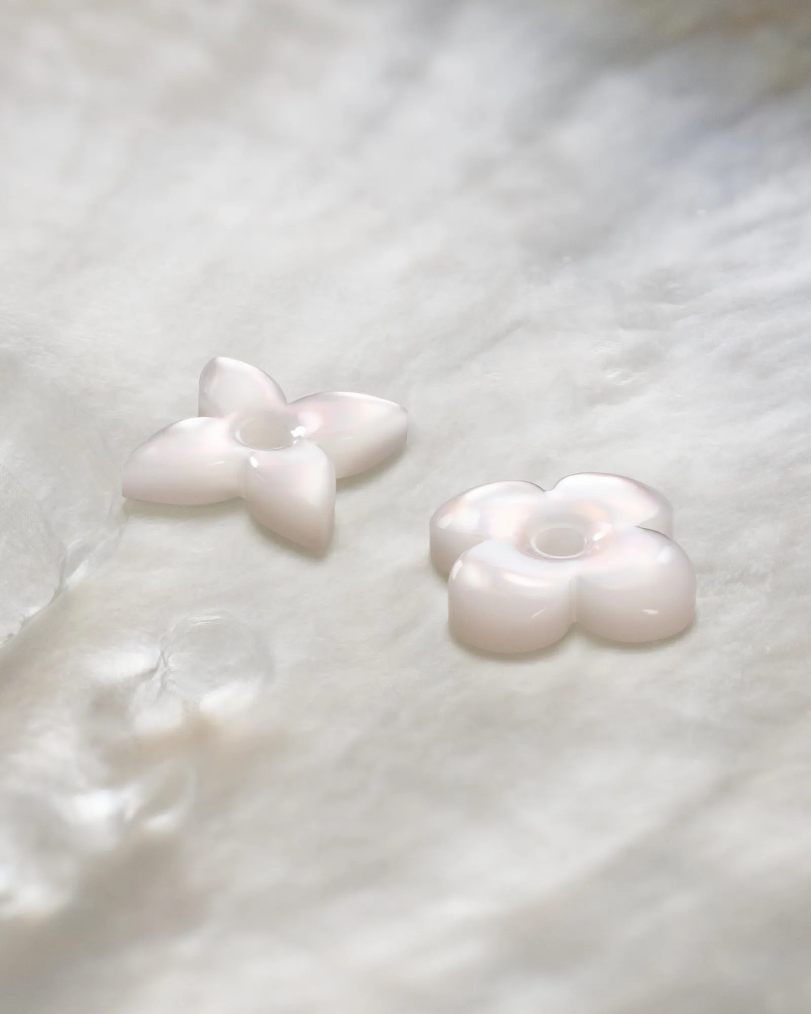 Close-up of several pale pink pearl-like seashells resting on soft white fabric.