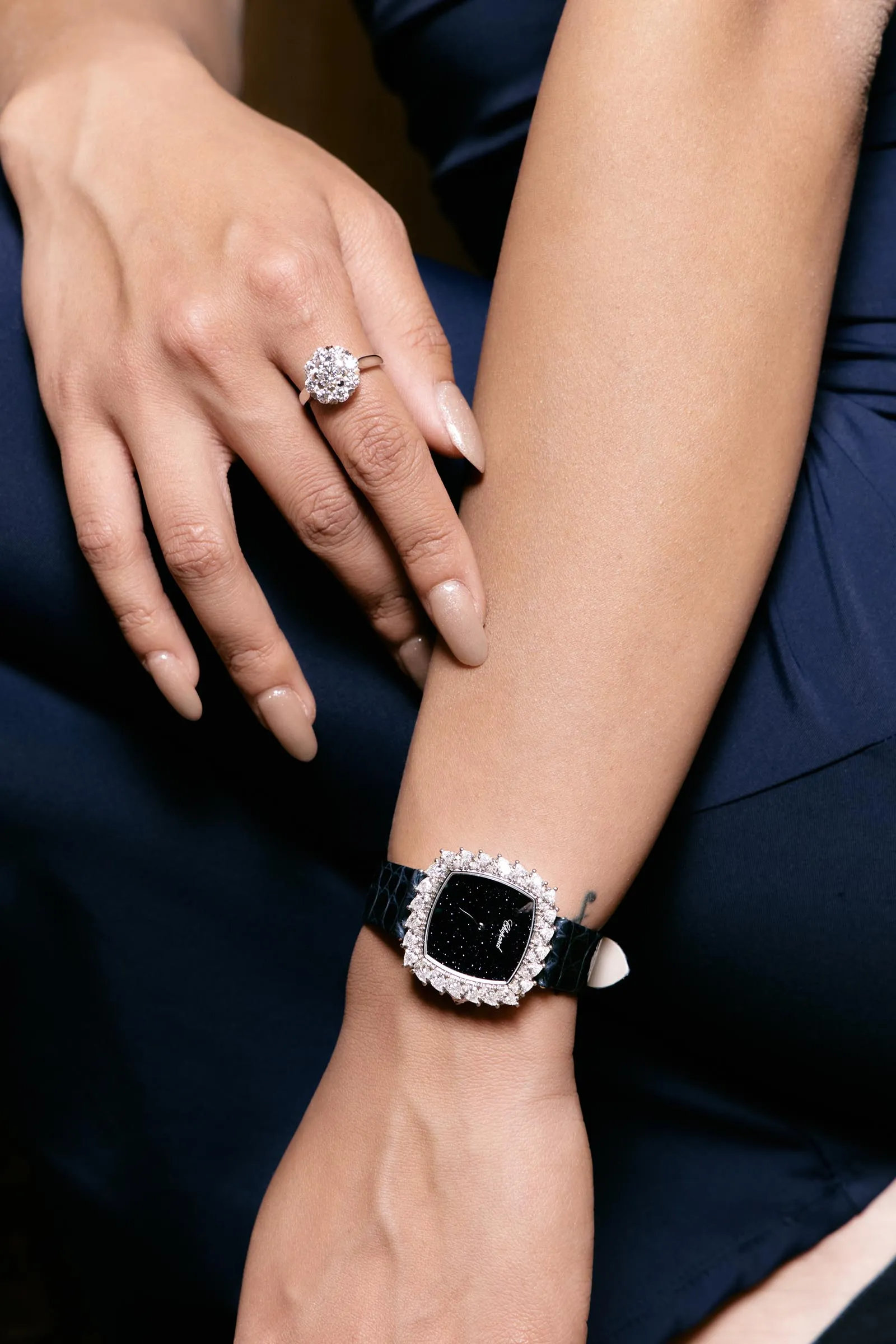 Close-up of a woman's left hand wearing a large diamond cluster ring on the ring finger.
