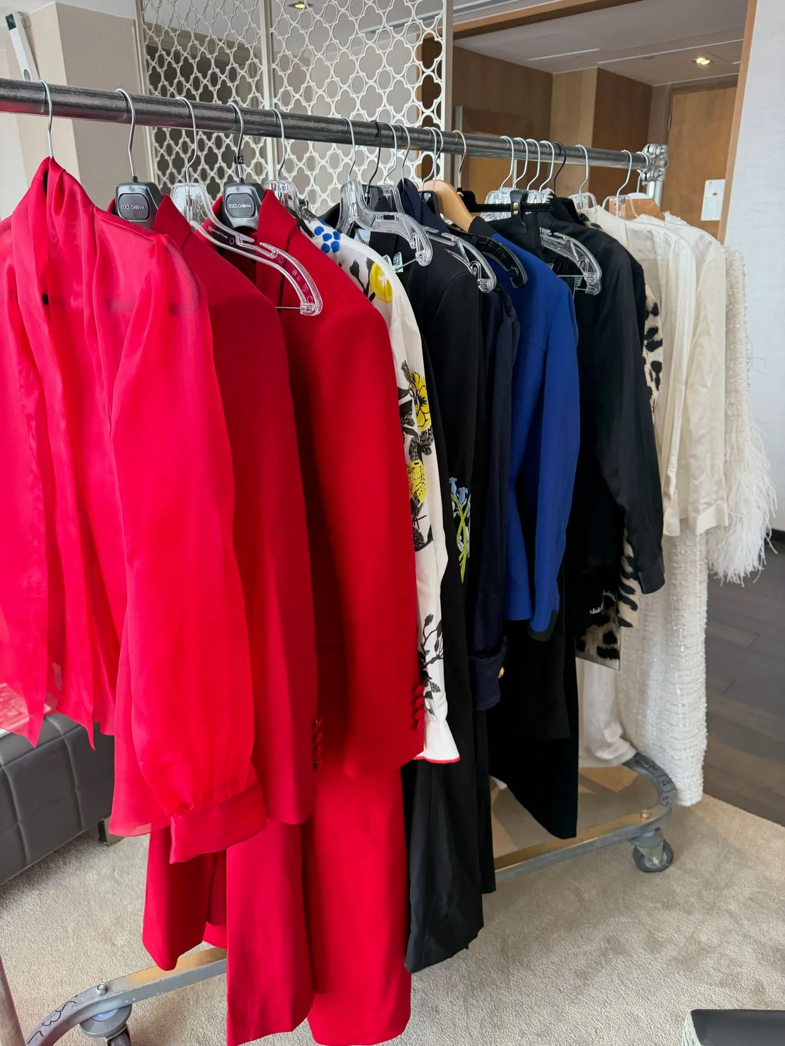Clothing rack with bright red dresses on the left and a row of navy, blue, black, and white dresses on a retail rack in a boutique.
