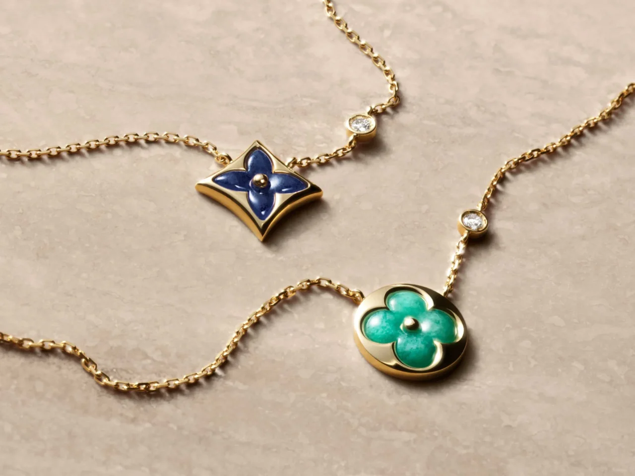 Gold chain necklace with a blue enamel four-leaf clover pendant and a small diamond accent against a neutral background