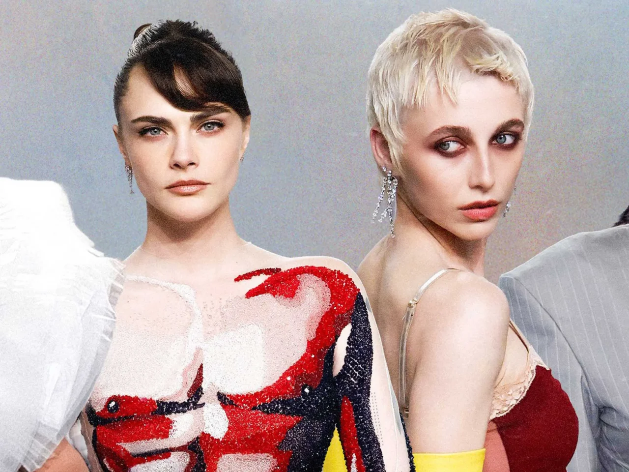 Group of four fashion models posing together in glamorous dresses for a shoot or runway backdrop.