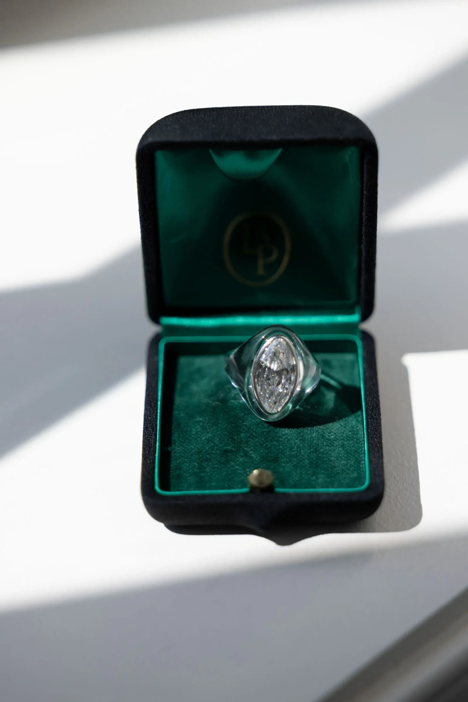 Diamond ring with a marquise-cut stone nestled in a green velvet jewelry box, open for display