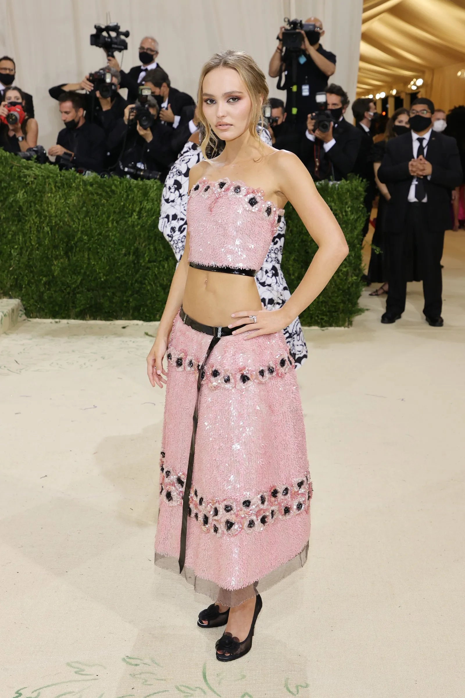 Woman in a pink sequin strapless dress posing for photographers at a formal event.