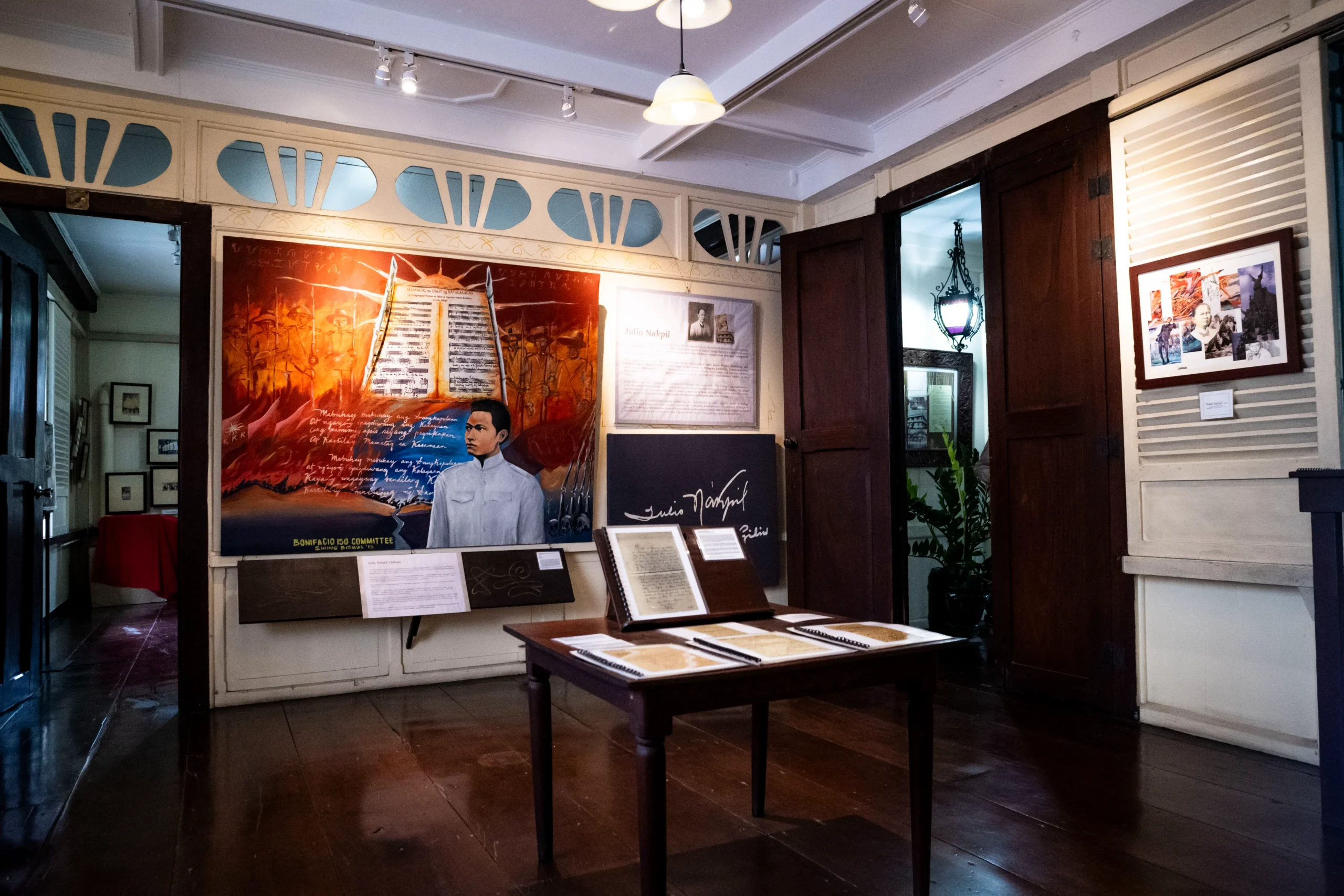 Museum gallery with large red poster showing a soldier, wall panels, and a central table displaying documents.