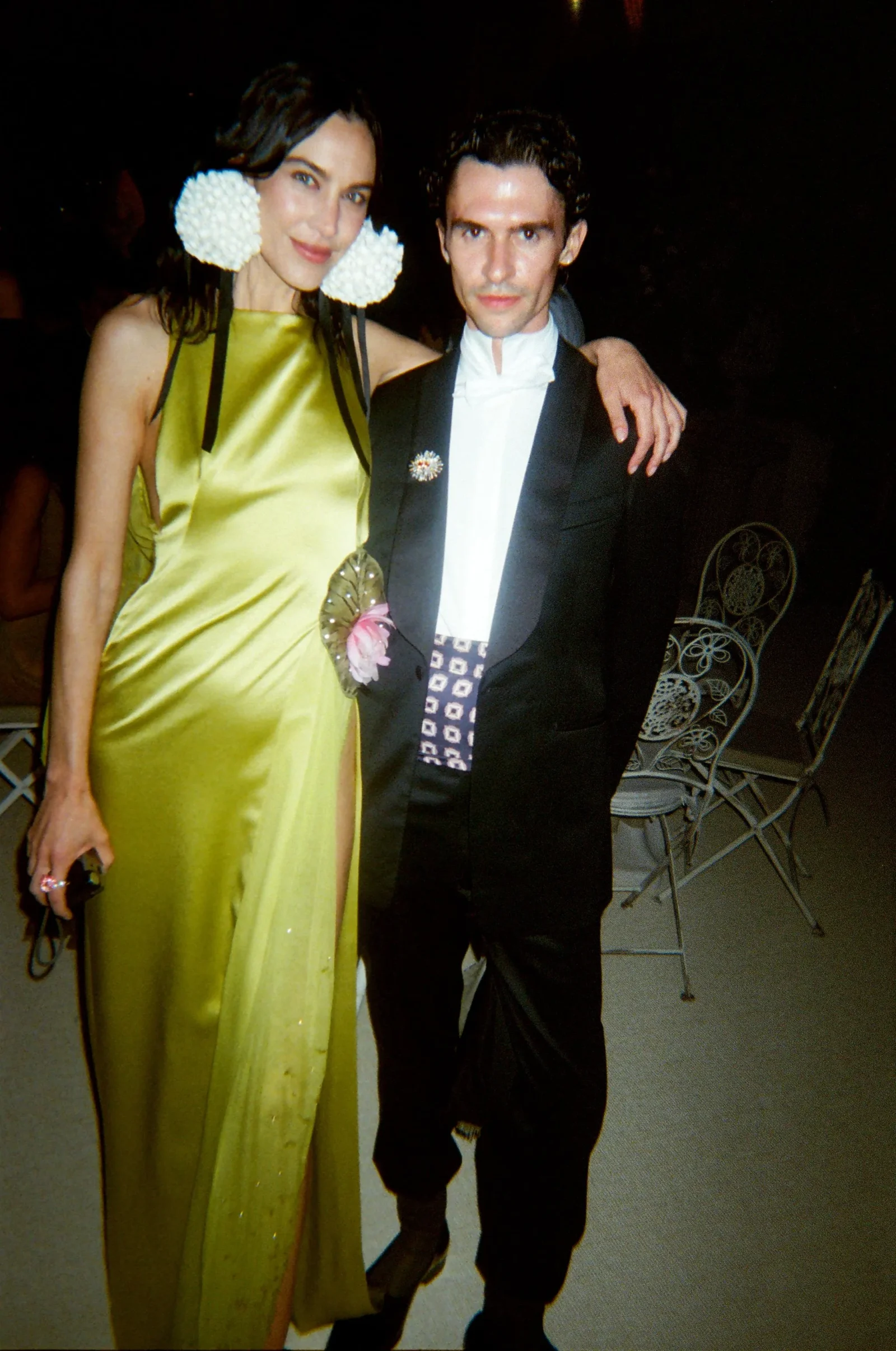 Woman in a lime satin gown posing with a man in a black suit at a formal event, her arm around his shoulders.