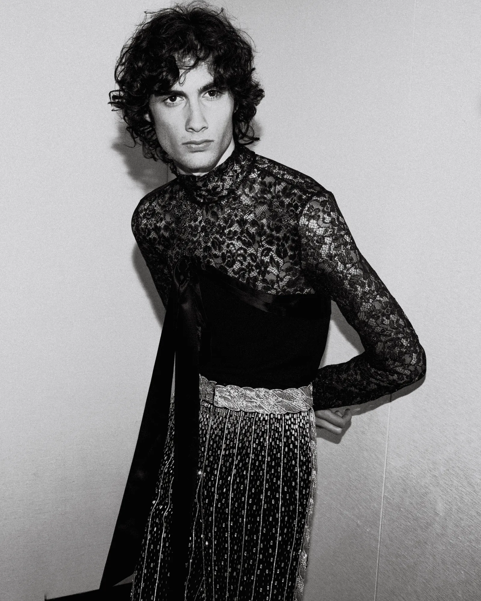 Black-and-white photo of a person in a high-neck lace top, looking to the left with a serious expression.