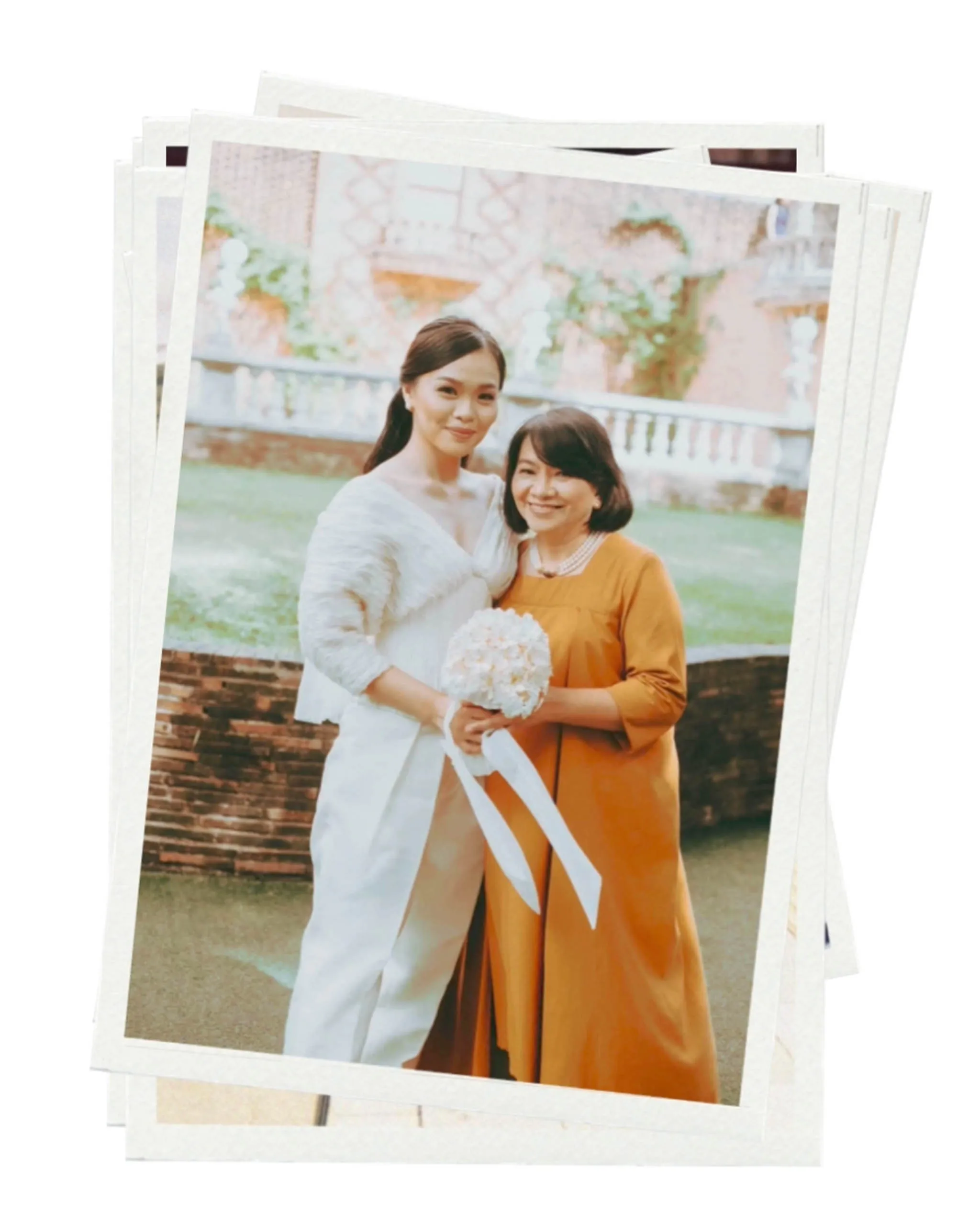Two women posing outdoors; one in a white dress holding a white bouquet, the other in an orange dress, smiling together.
