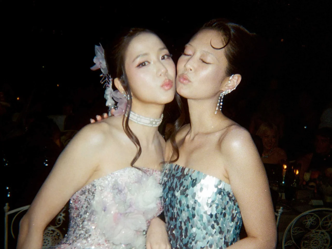 Two women posing closely for a nighttime selfie, smiling at the camera with jewelry visible
