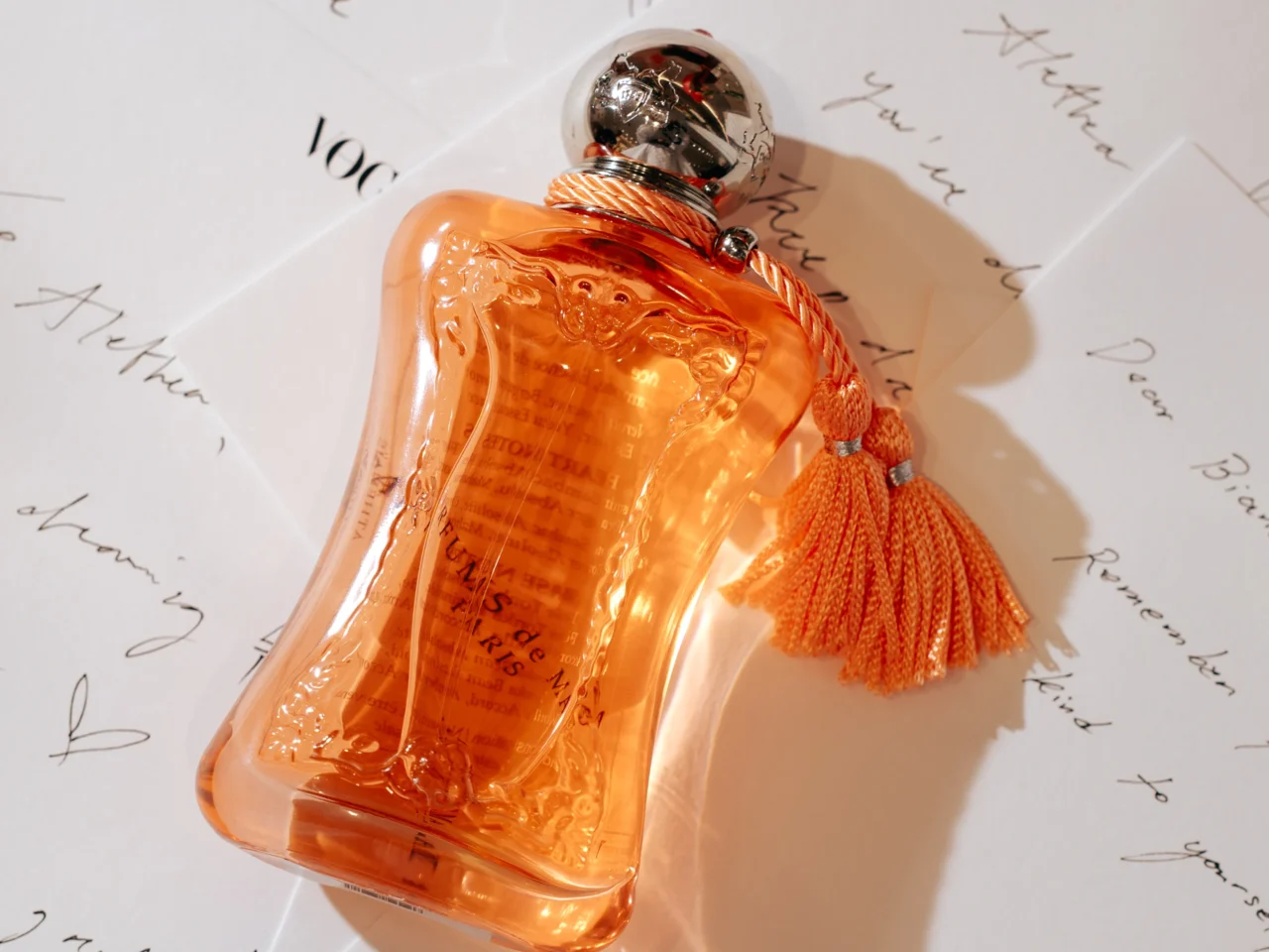 Parfum de Marly Athénaïs Fragrance Bottle on top of notecards written by guests.