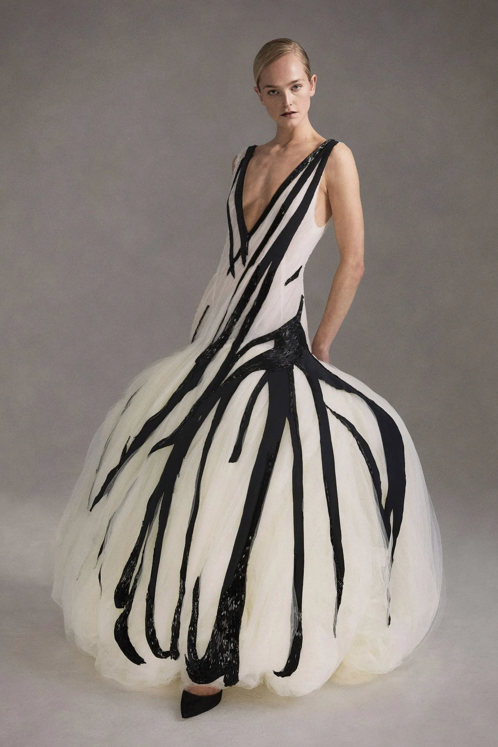 Model wearing a white gown with bold black vertical stripes and a voluminous tulle skirt.