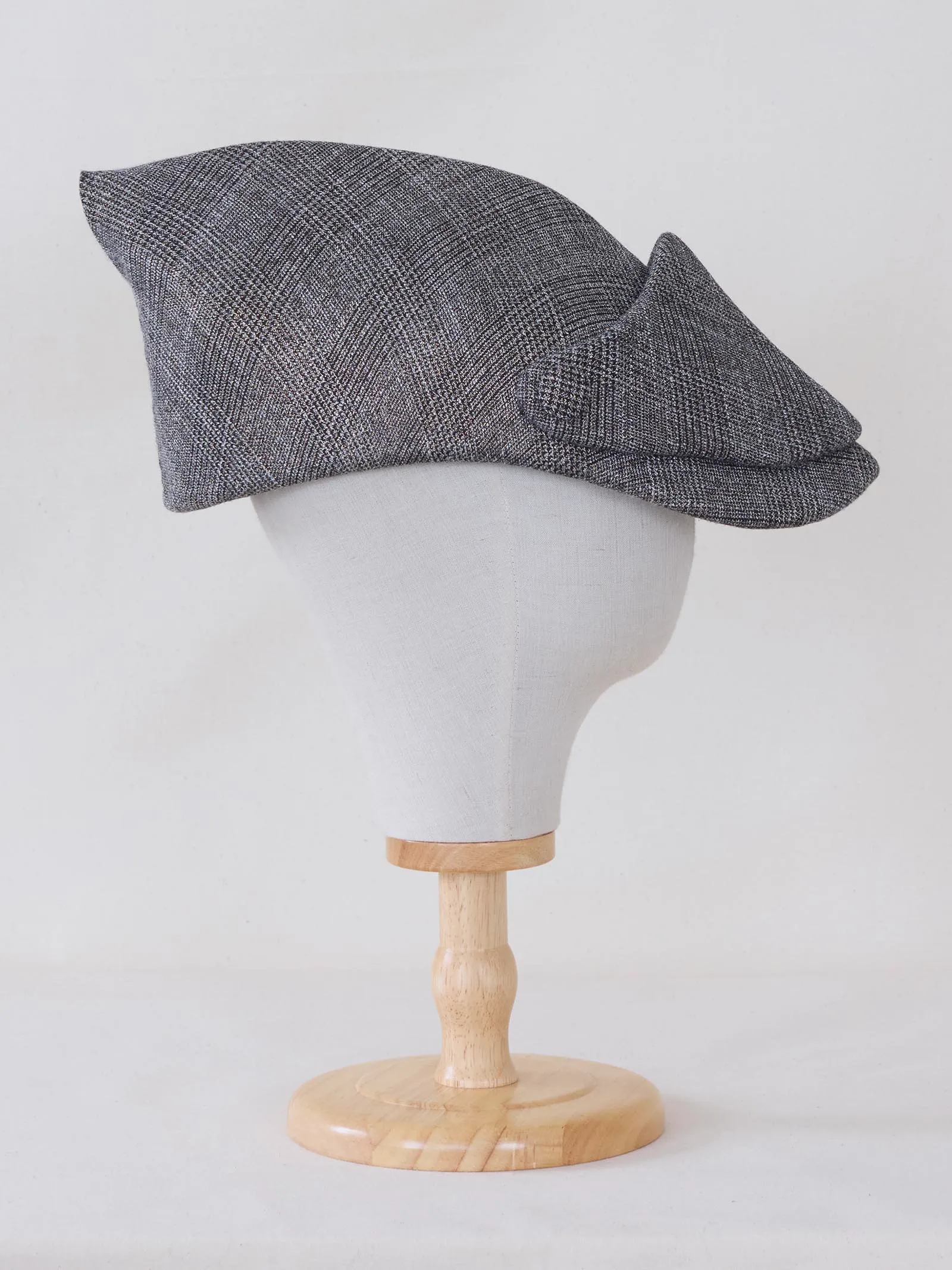 Grey tweed flat-cap displayed on a mannequin head on a wooden stand