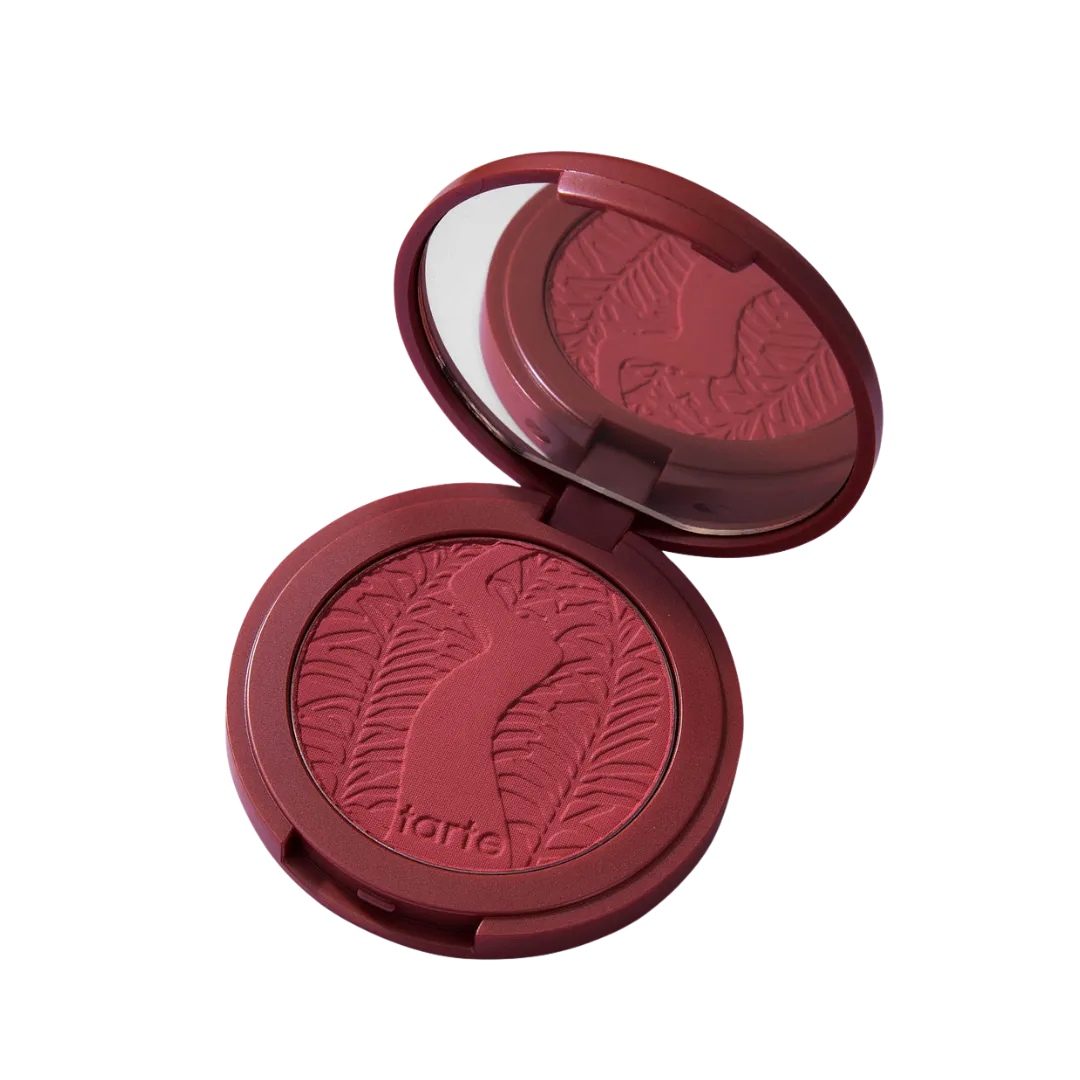 Red round blush compact with engraved leaf pattern and mirror, lid open and product visible in foreground.