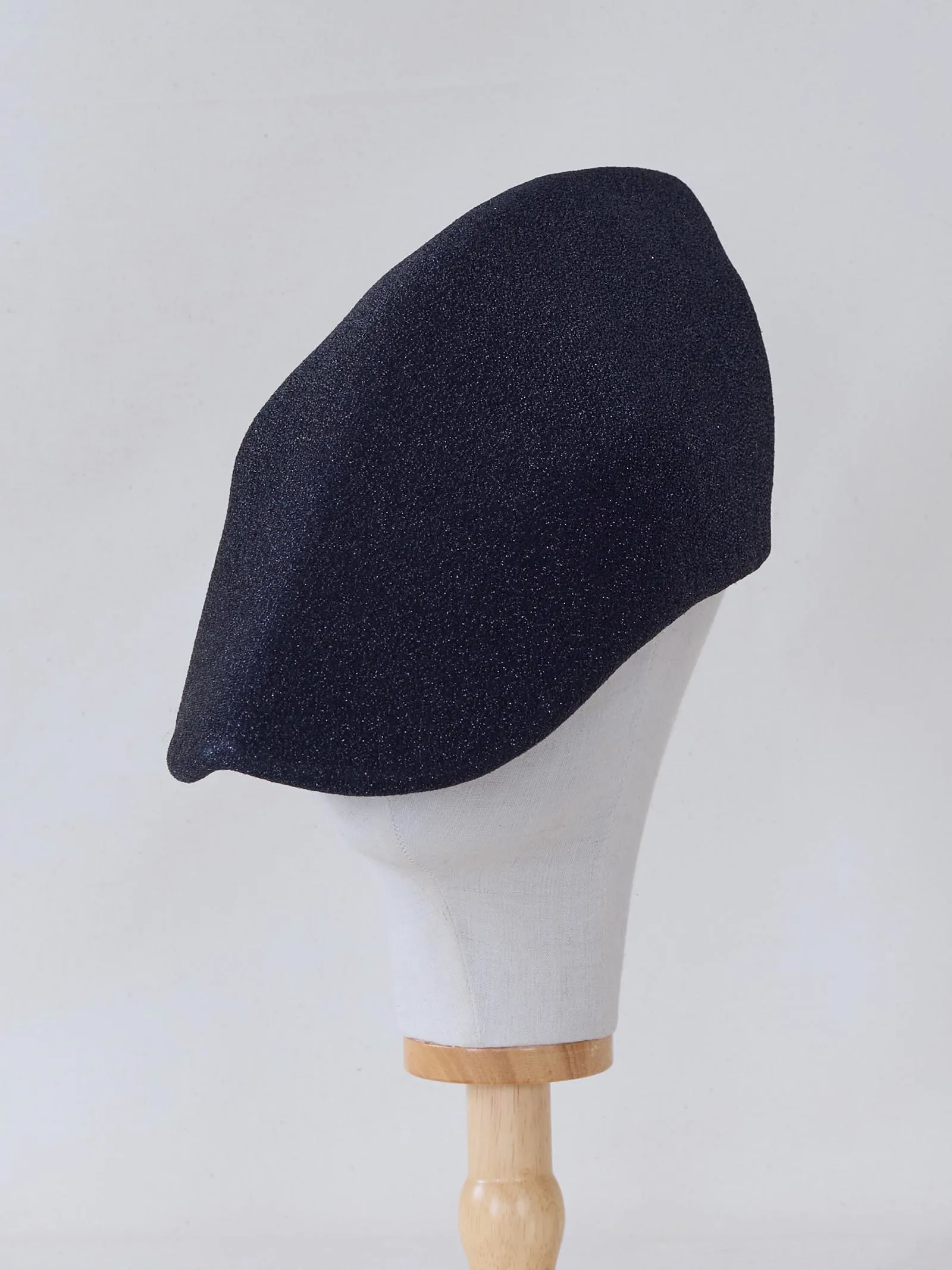 Dark navy glitter beret worn on a white mannequin head against a light background, angled to show its side profile.