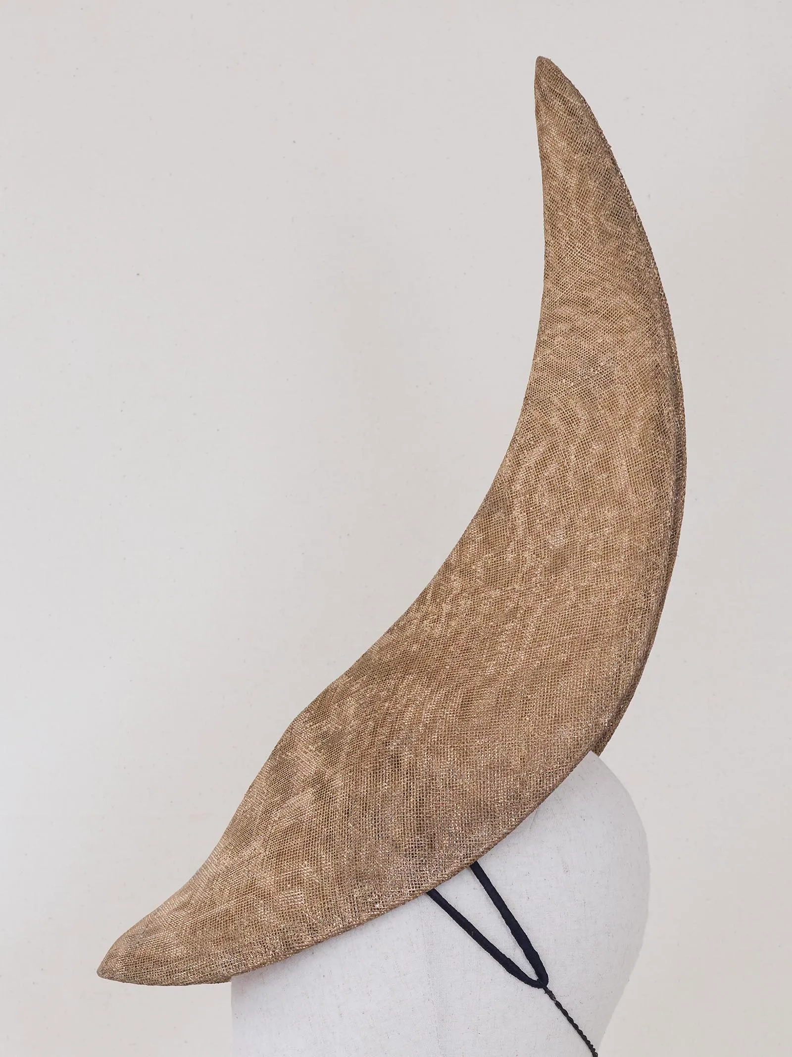 Beige textured wide-brim hat sitting on a white dress form against a light background, photographed from the side