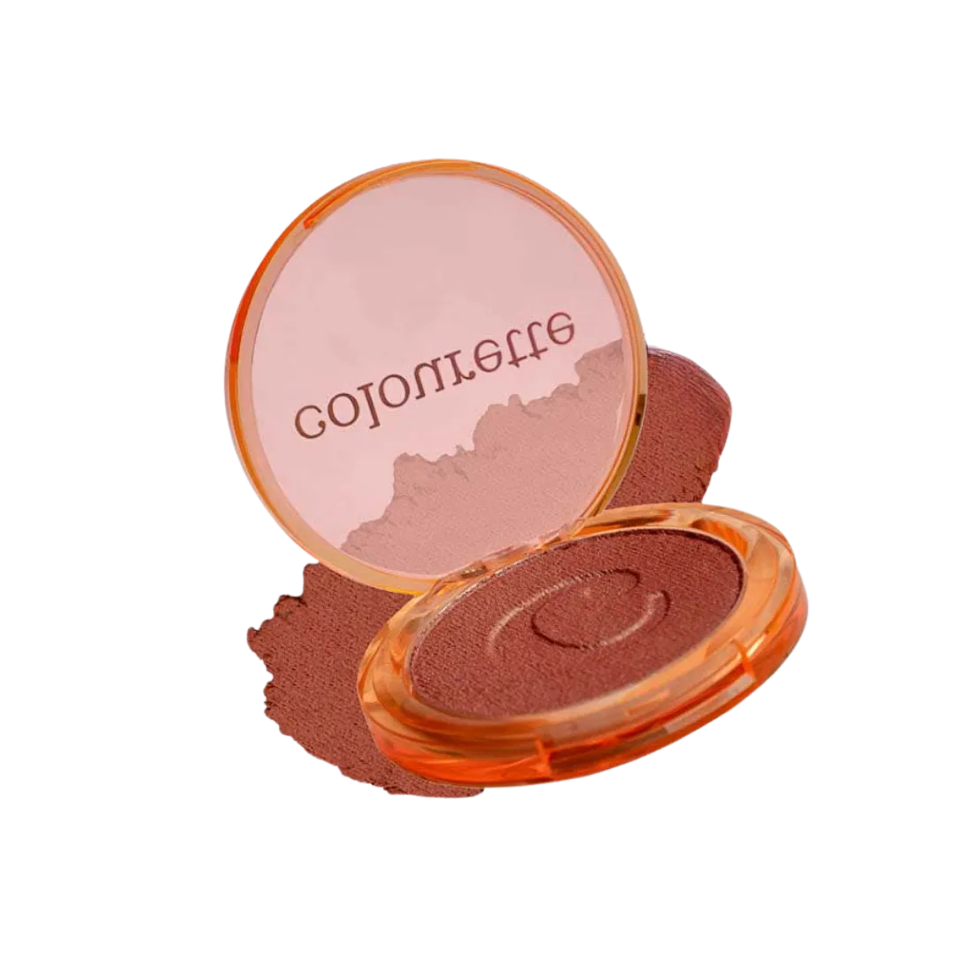 Open peach-colored powder compact with a pink pressed powder and a mirror lid showing blurred text, surrounded by loose powder spill