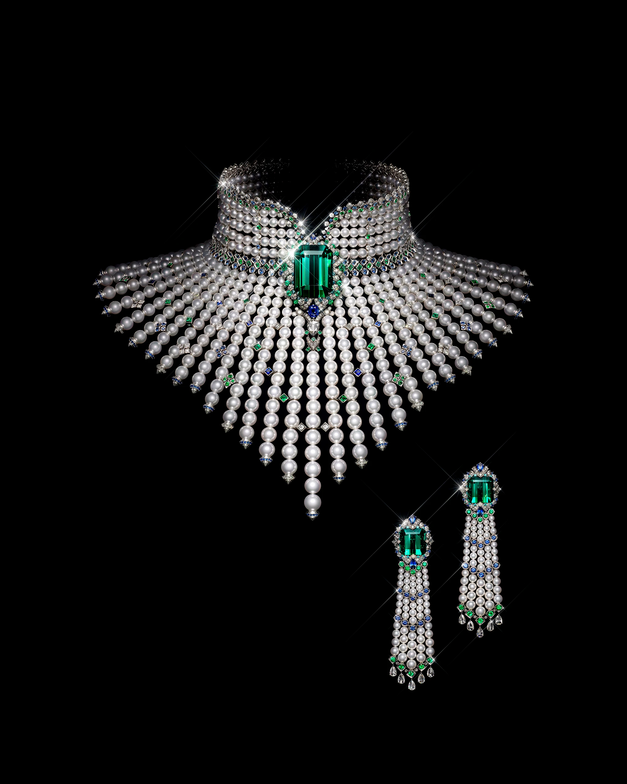 Opulent pearl and diamond choker with a large green emerald centerpiece set against a black background, cascading pearl strands below