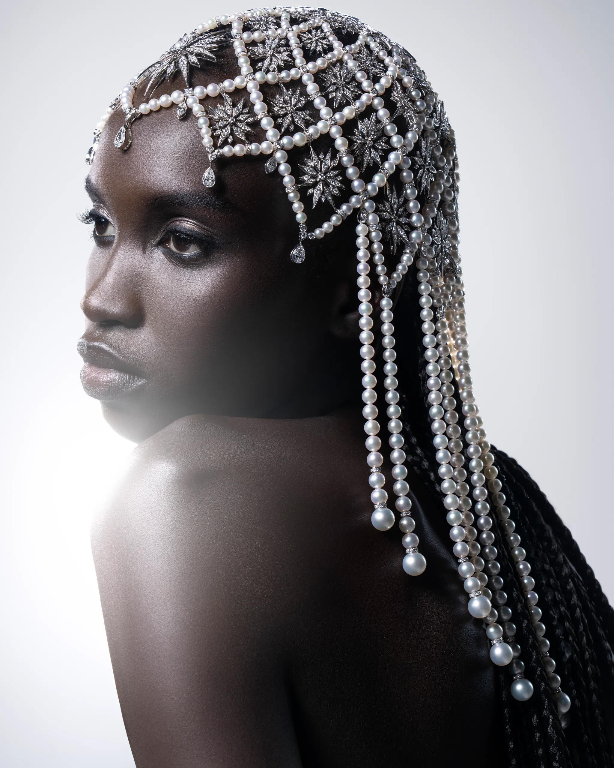 Close-up of a Black woman wearing an elaborate pearl headpiece with silver star ornaments.