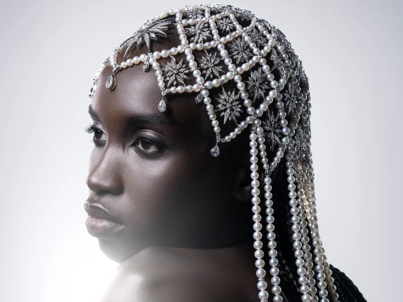 Close-up of a dark-skinned woman with an elaborate pearl and crystal headpiece cascading over her hair.