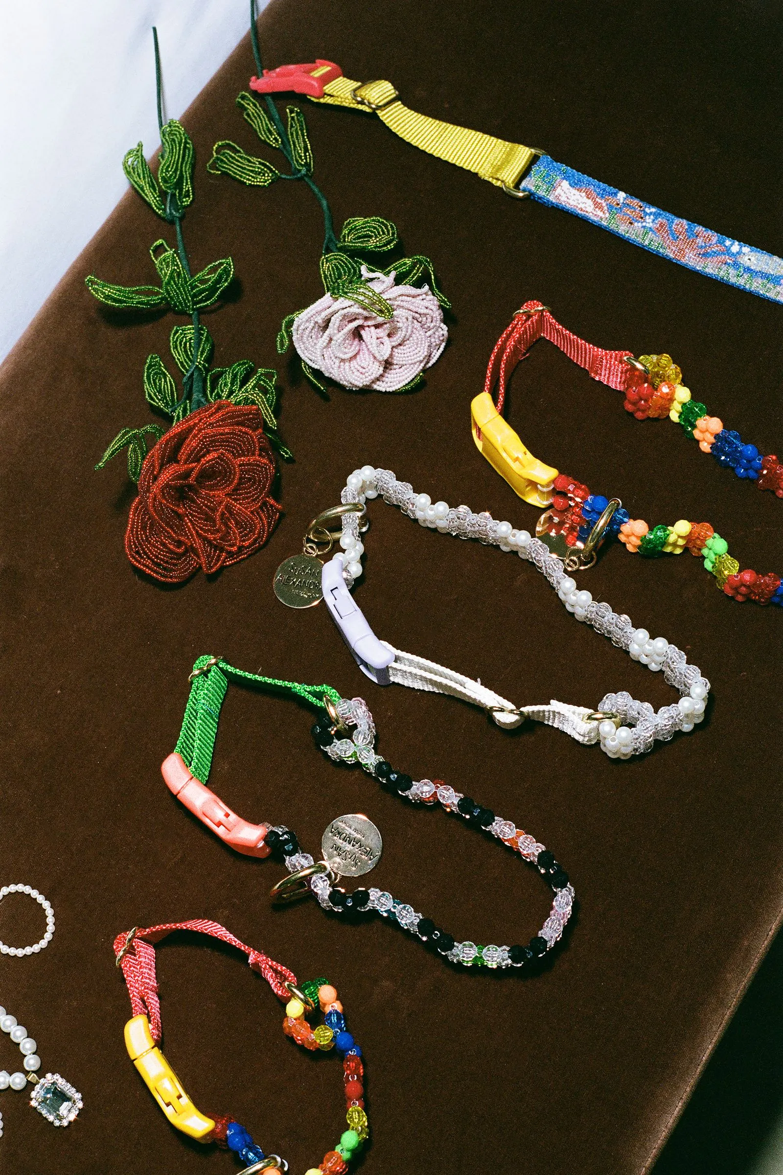 Assortment of handmade beaded jewelry, including flower-shaped beadwork and colorful bracelets on a dark table surface