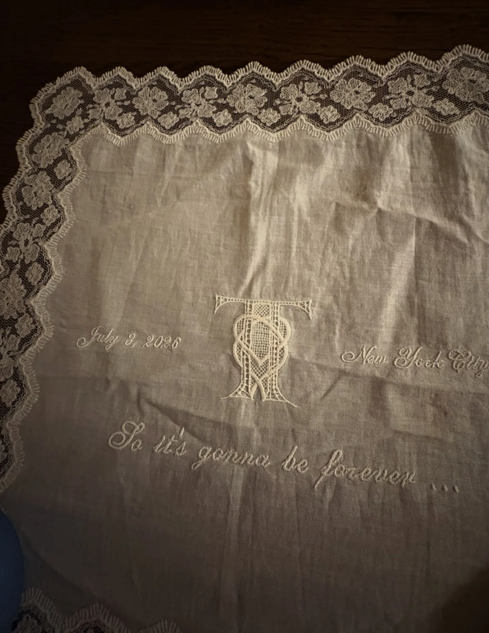 Linen fabric with a floral lace border and white embroidery, including the date 'July 2, 2008' in cursive.