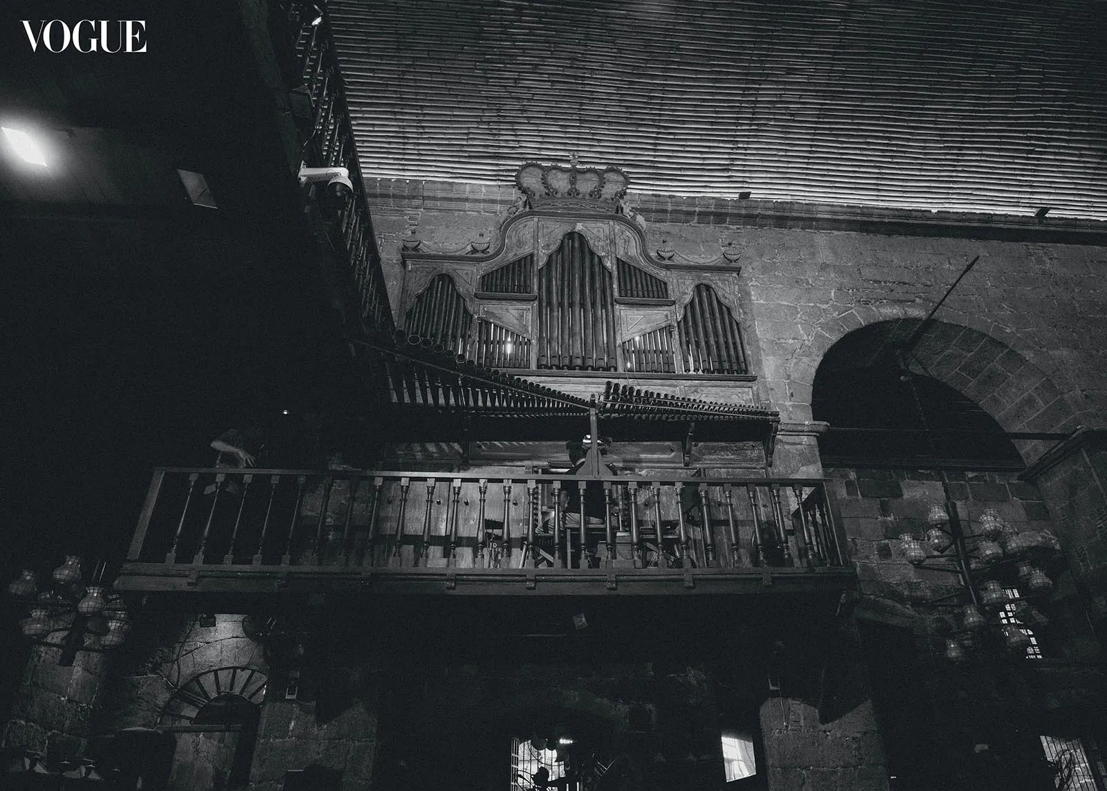 Dimly lit historic church interior with a large ornate pipe organ above a wooden balcony railing.