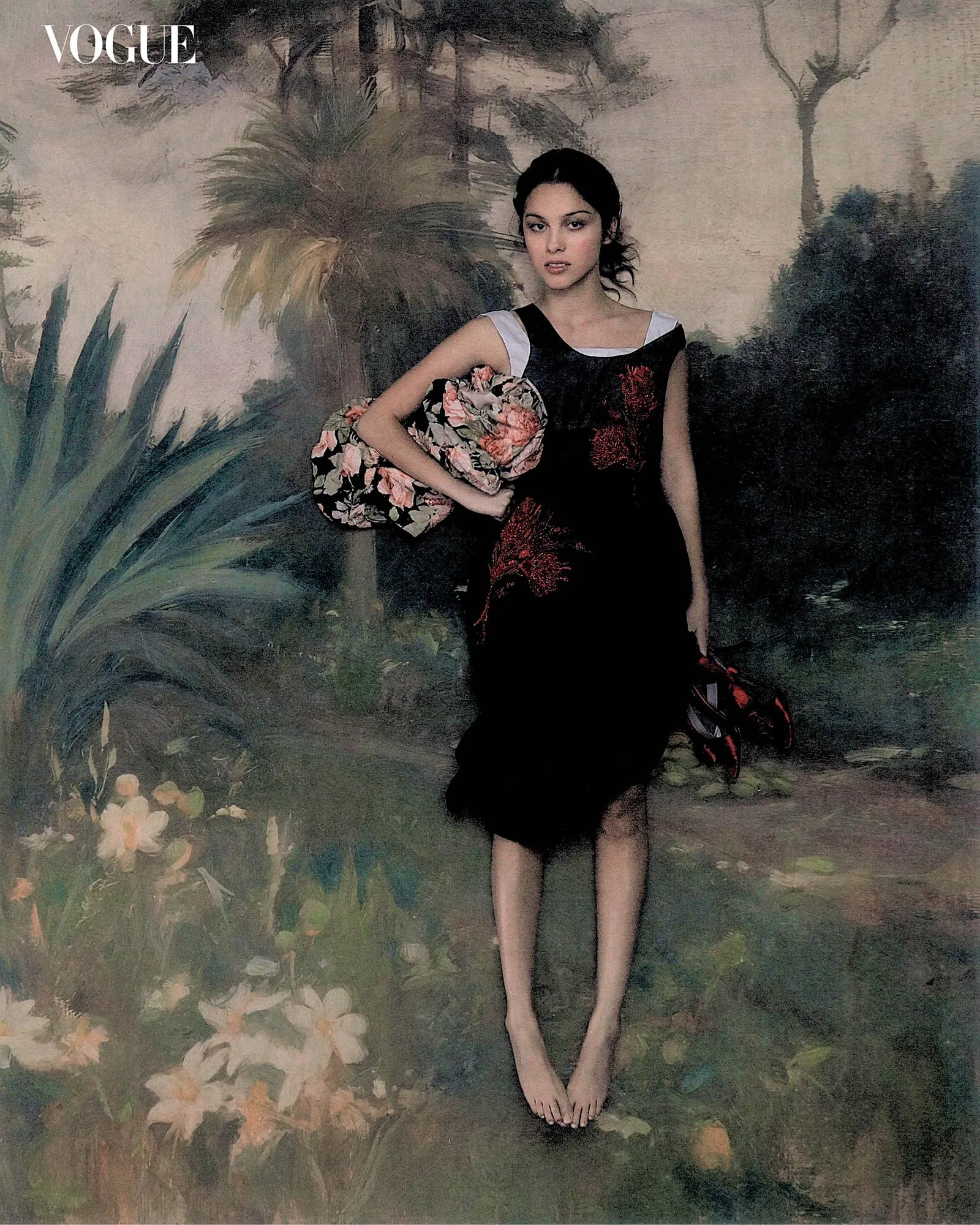 Model in a black floral dress standing barefoot in a painted garden backdrop, holding a matching floral clutch; Vogue logo in the top-left corner.
