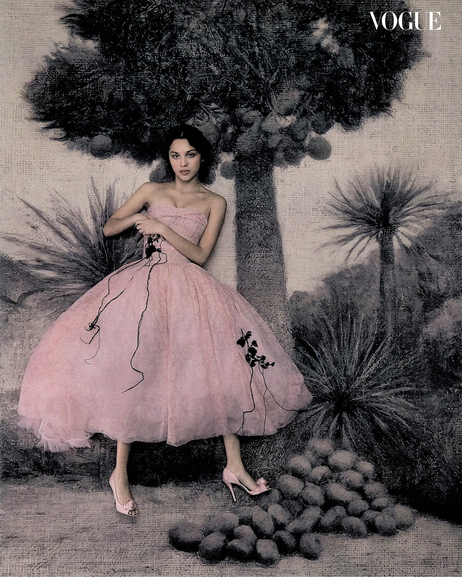 Model in a pink strapless gown sits among large stylized plants with a tree behind her; Vogue logo appears in the top right.