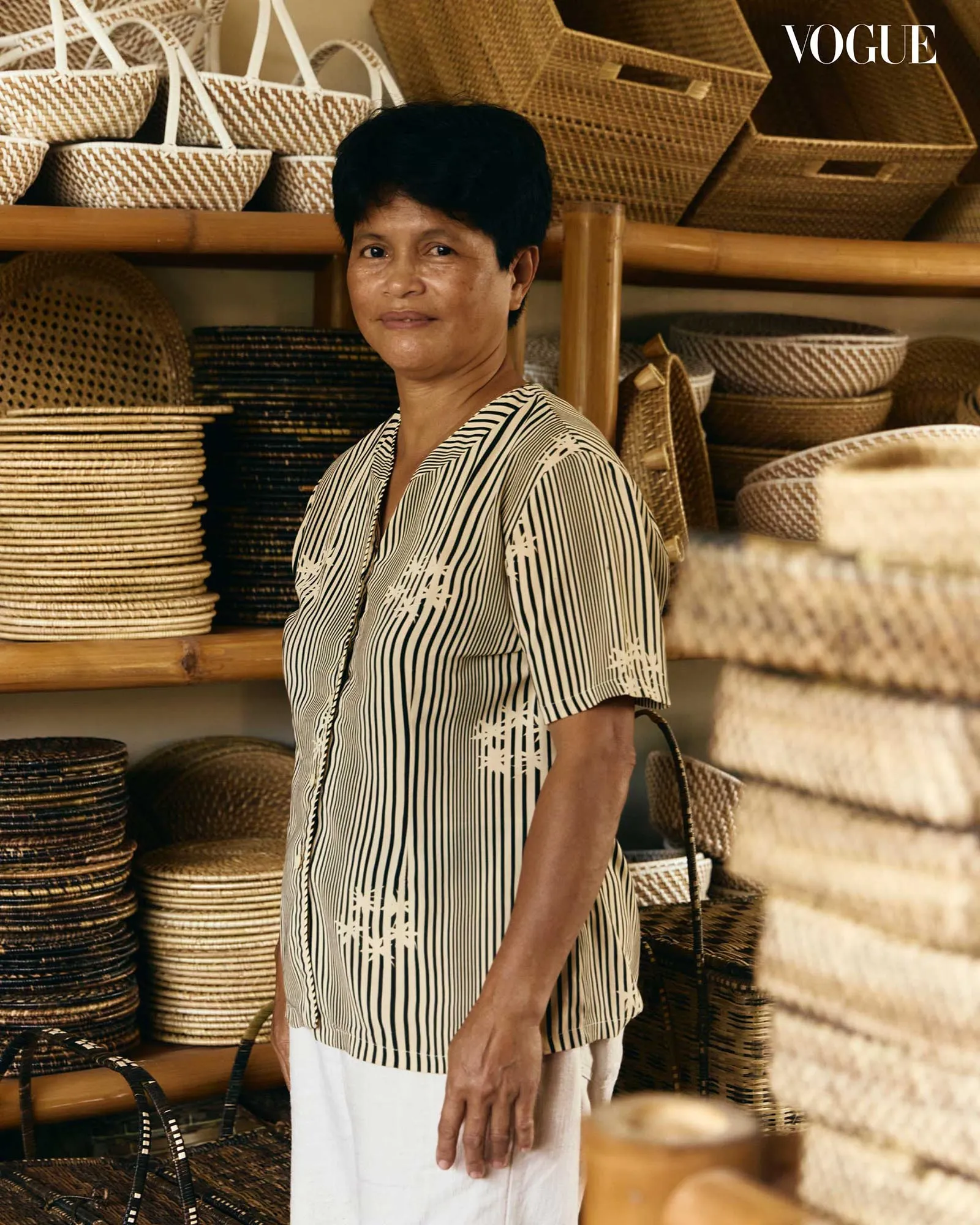 Woman in a wicker basket shop, surrounded by baskets on shelves; Vogue logo top-right.