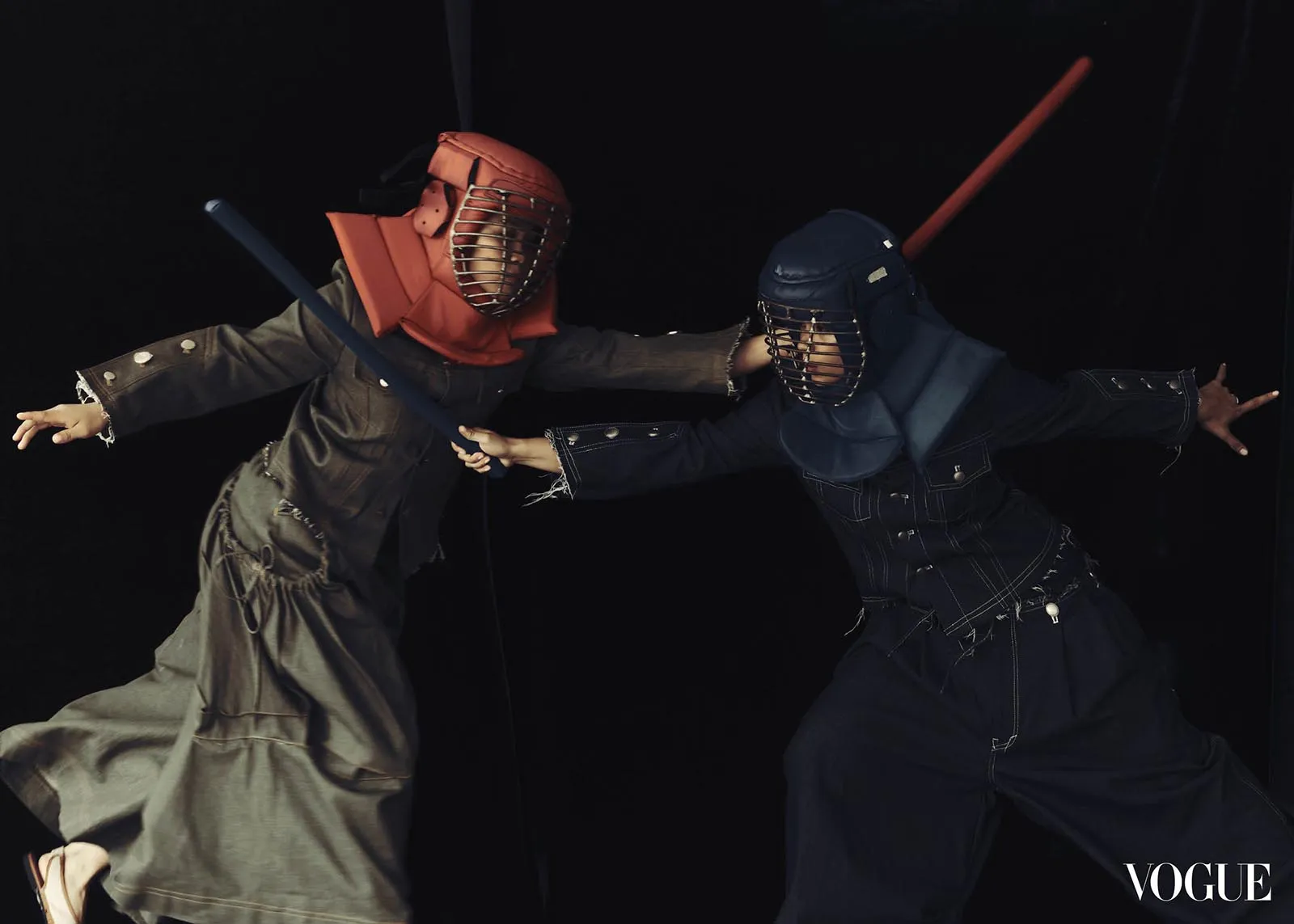 Two people in red and blue kendo armor duel with swords in a dark studio; Vogue logo in the corner.