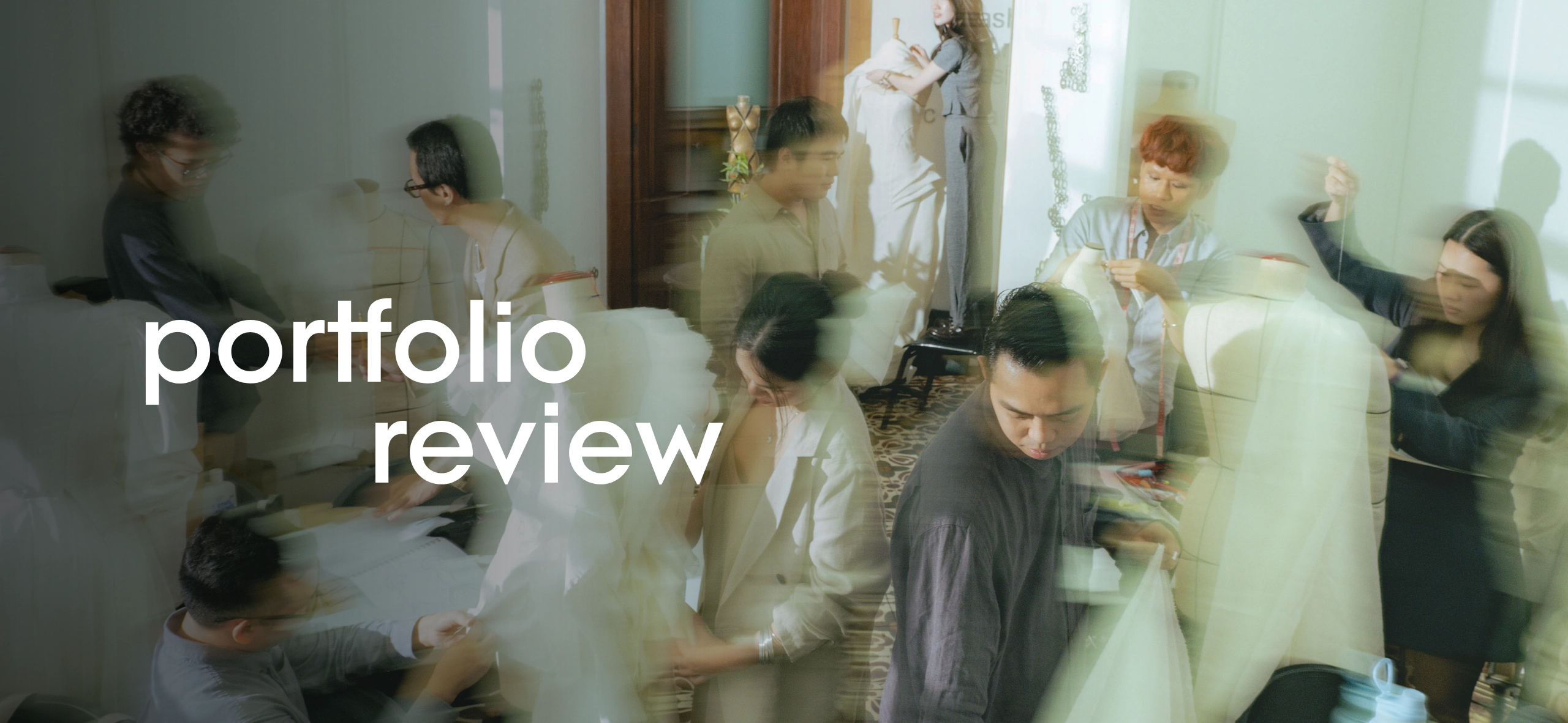 Busy studio scene with multiple people reviewing portfolios around a table, overlaid by large 'portfolio review' text for emphasis.