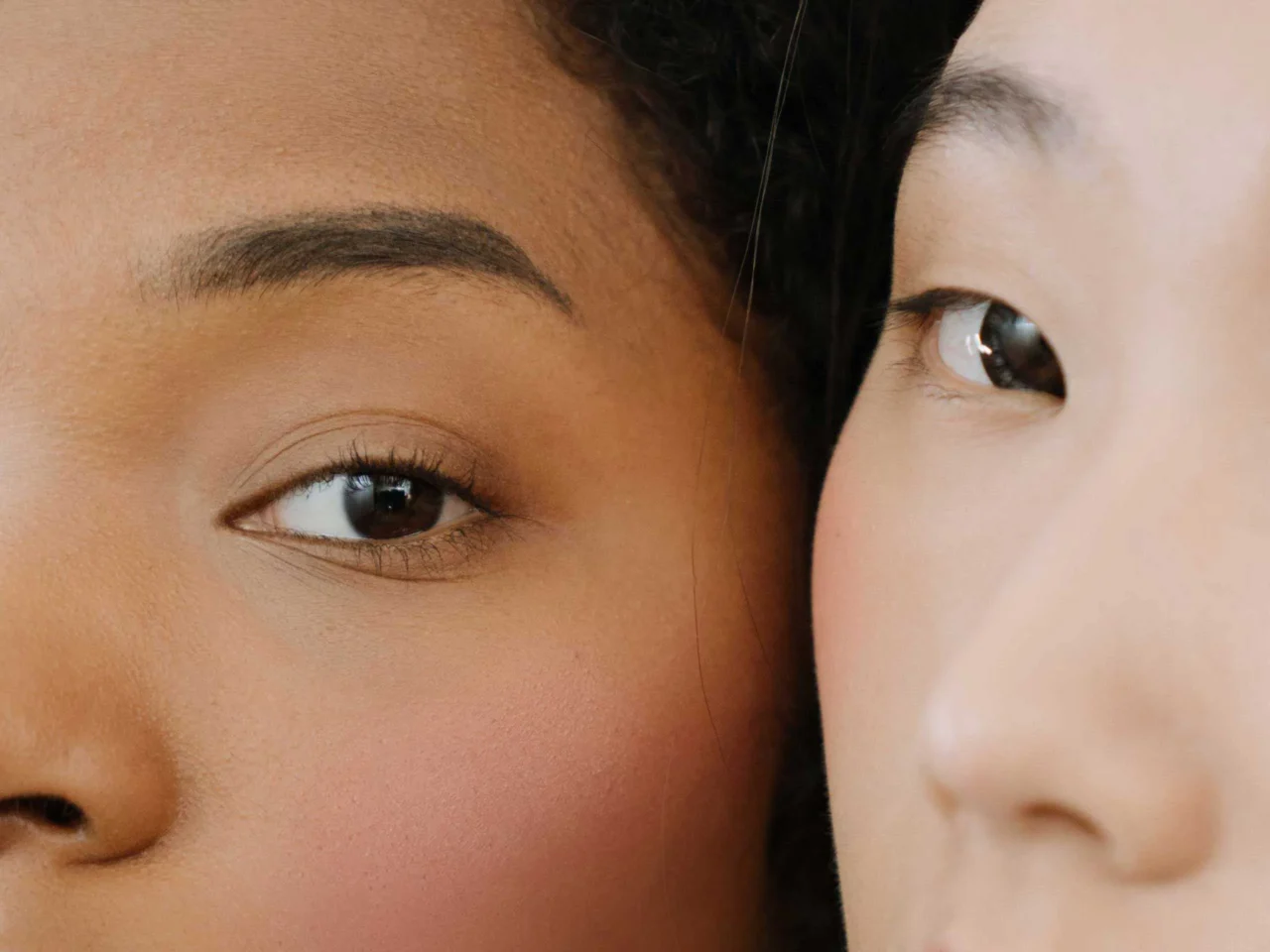 Close-up of two faces pressed together, showing the left person’s eye and the right person’s cheek and eye partially visible.