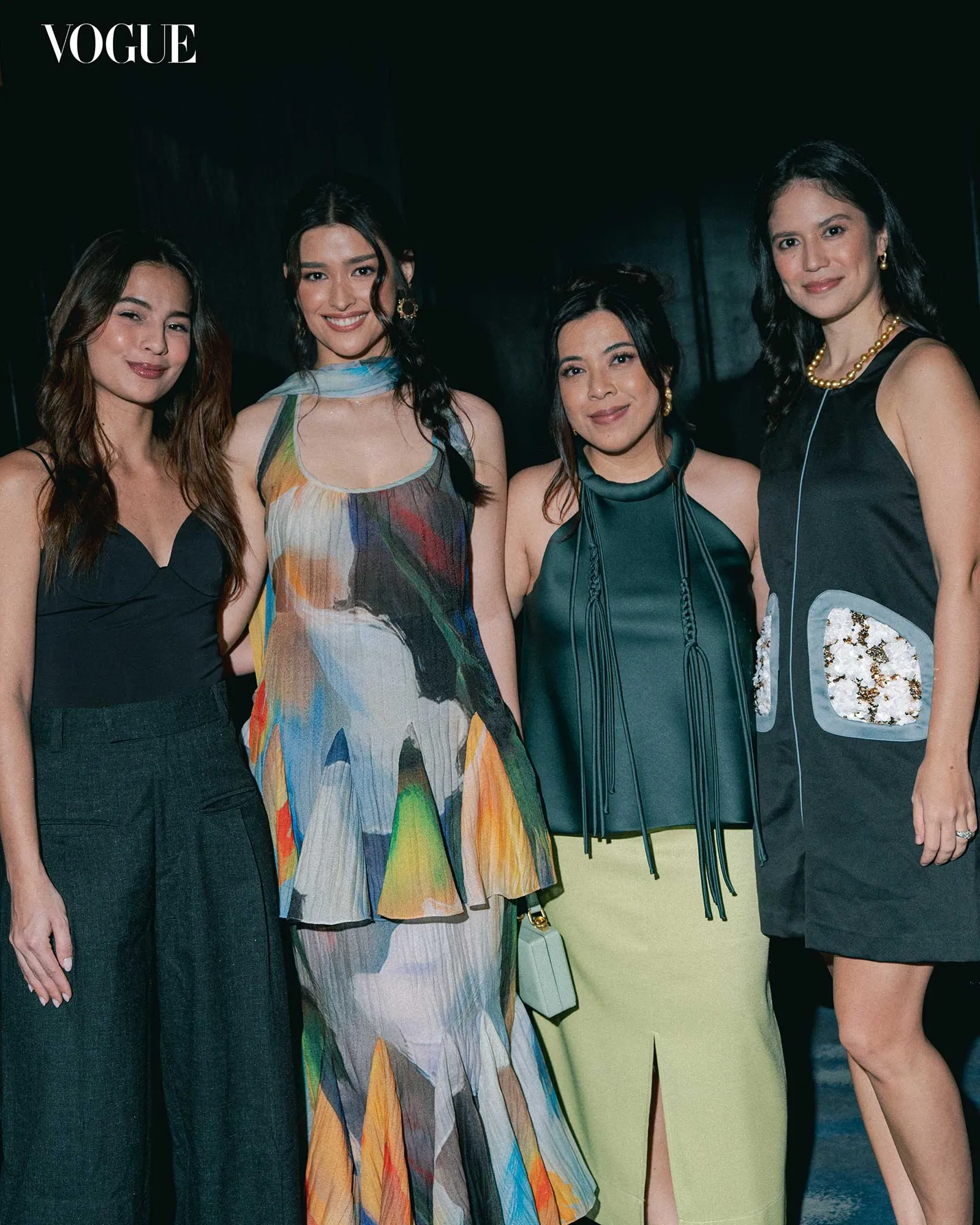 Four stylish women posing together at a fashion event, Vogue logo top-left visible.