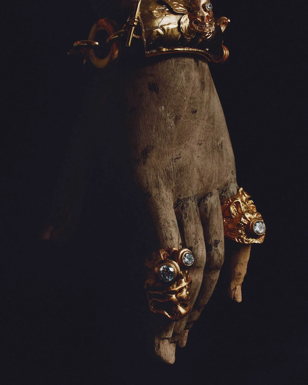 Close-up of antique metal armor pieces with riveted studs on a dark red background.