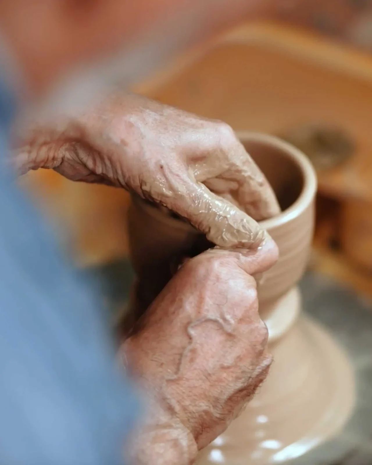 Elderly woman and man sit at a wooden dining table in a cozy home, chatting and smiling.
