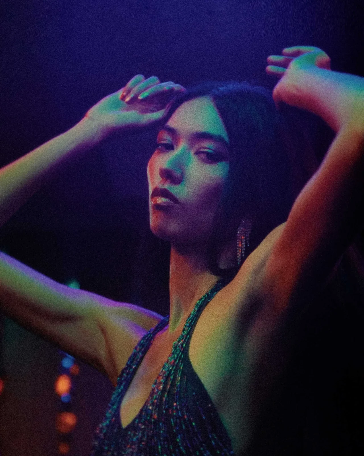 Dancers in a dark club under purple-blue neon lights, facing each other as they move to the music.